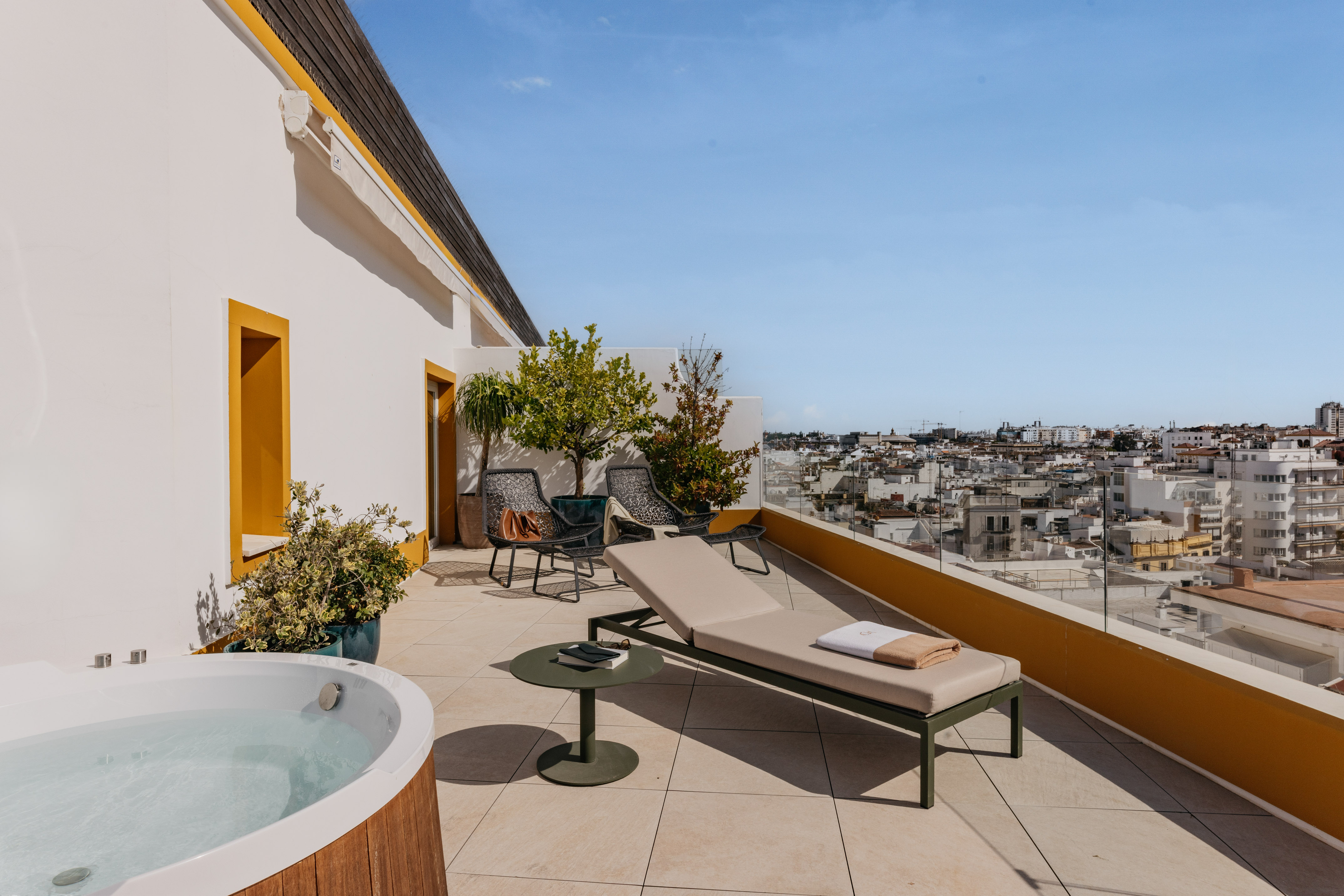 Terraza azotea con jacuzzi, tumbona y vistas a la ciudad.