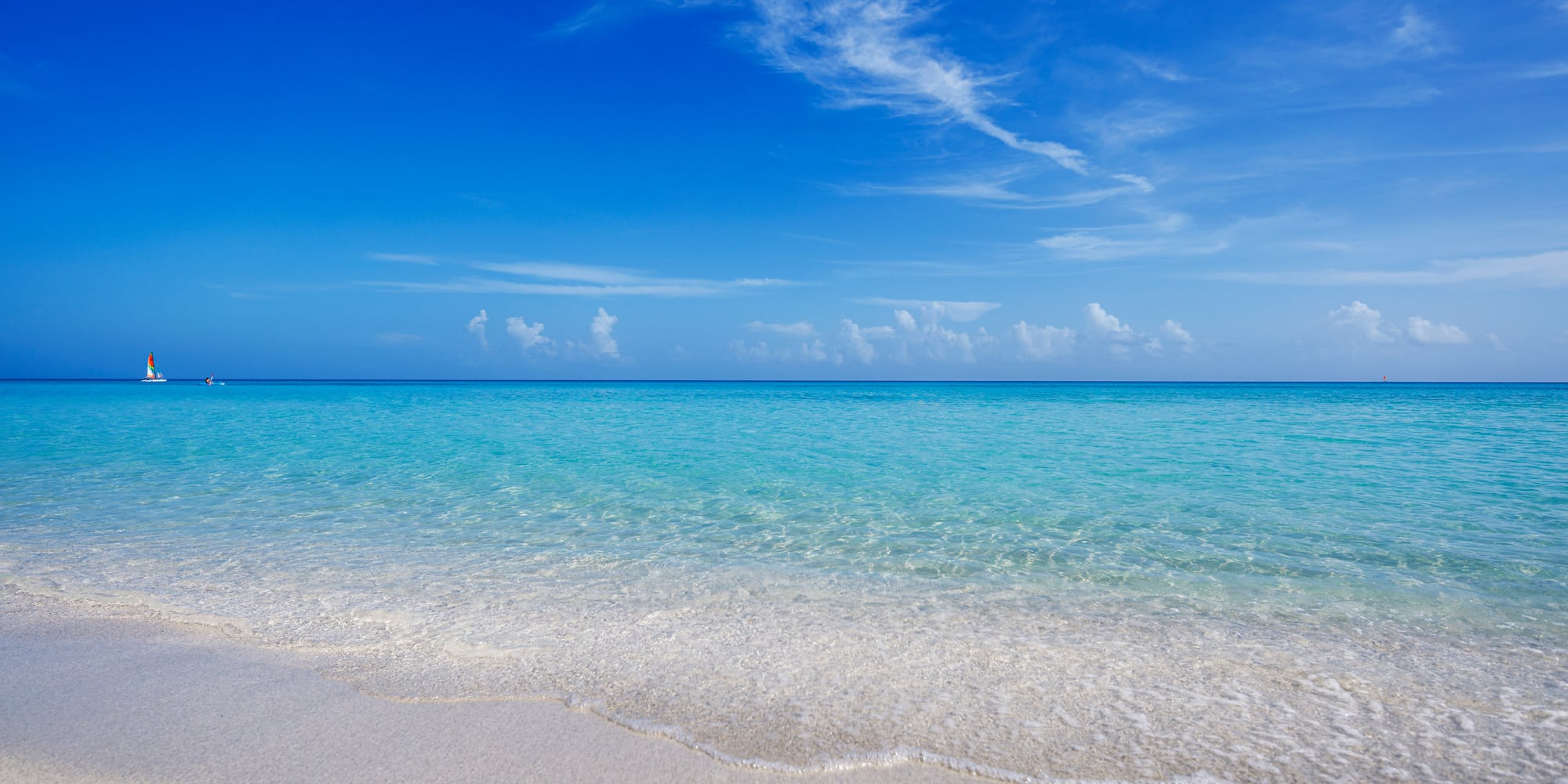 a beach with clear water and blue sky