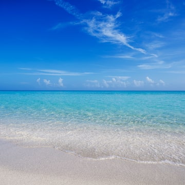 a beach with clear water and blue sky