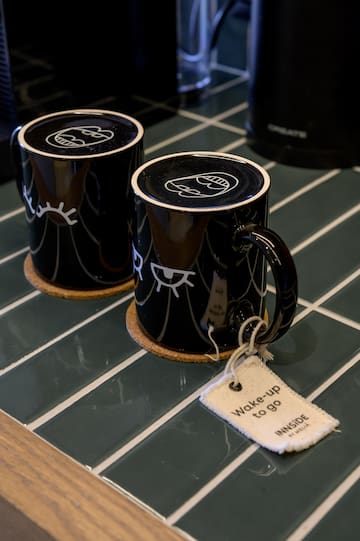 two black coffee mugs with white faces on them