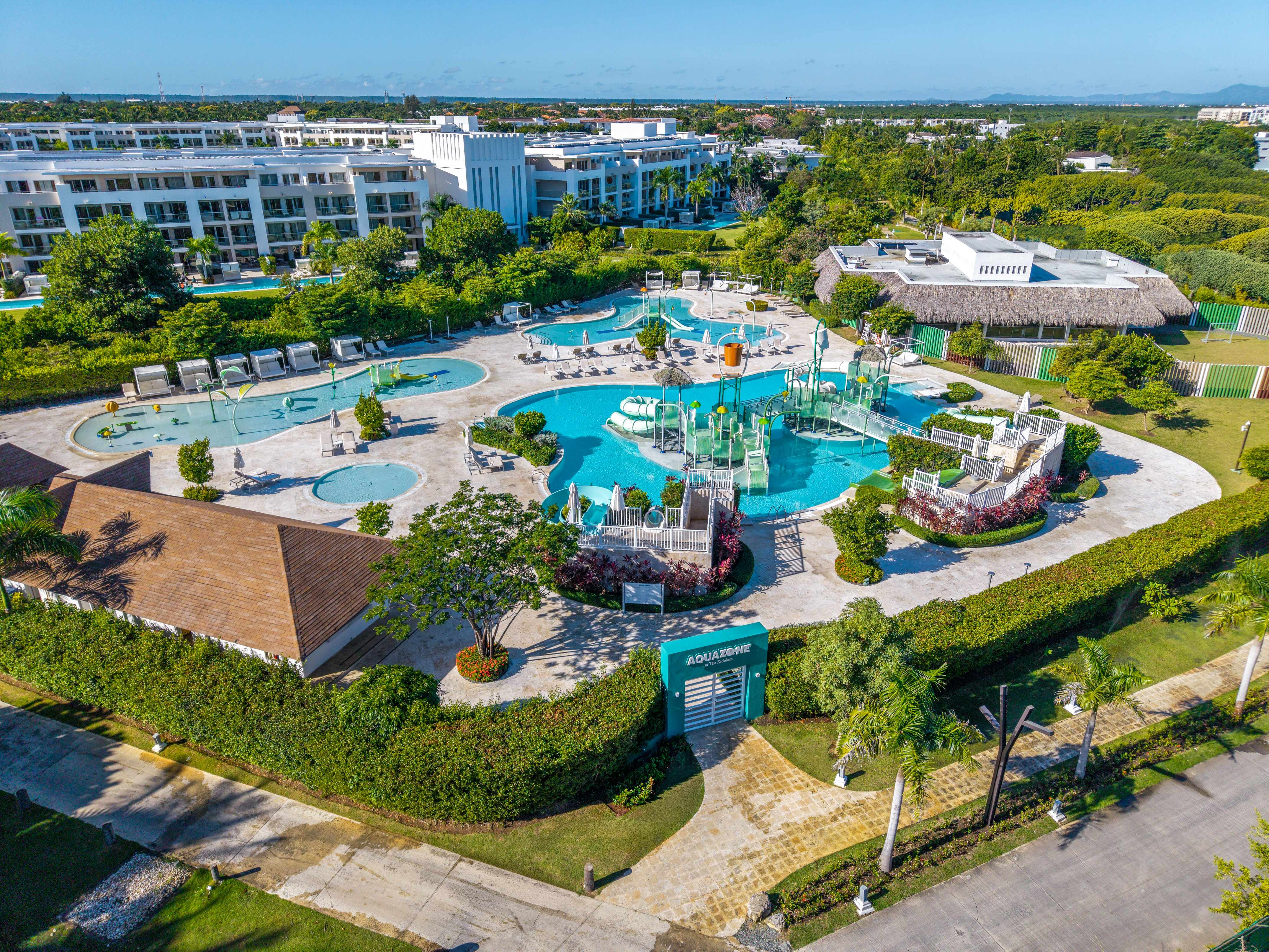 Aerial of Aquazone water park, resort pools, modern hotel buildings, tropical setting.
