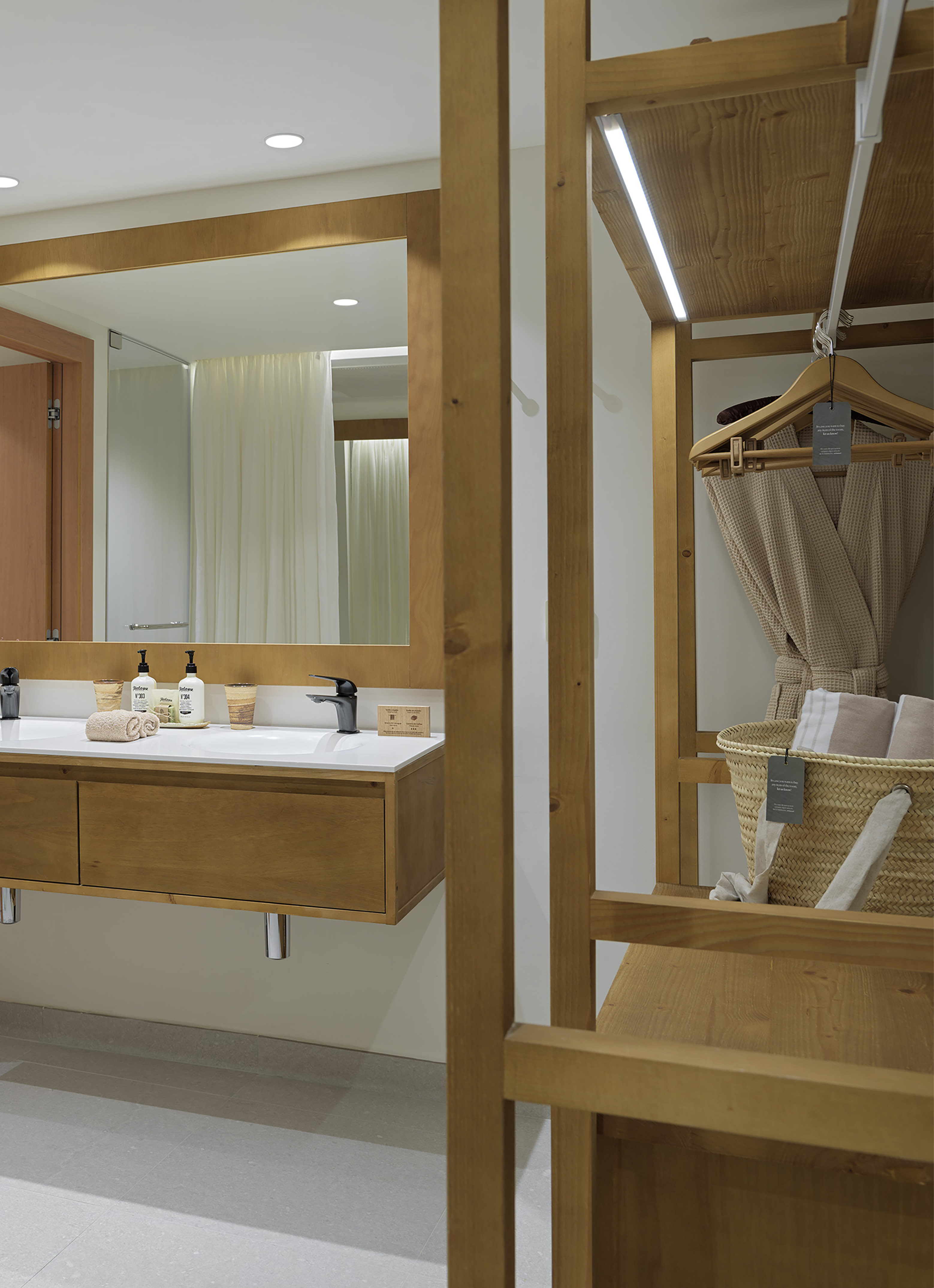Modern bathroom with wooden double vanity, black faucets, and open wood closet.
