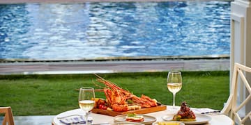 a table with food and wine glasses on it by a pool