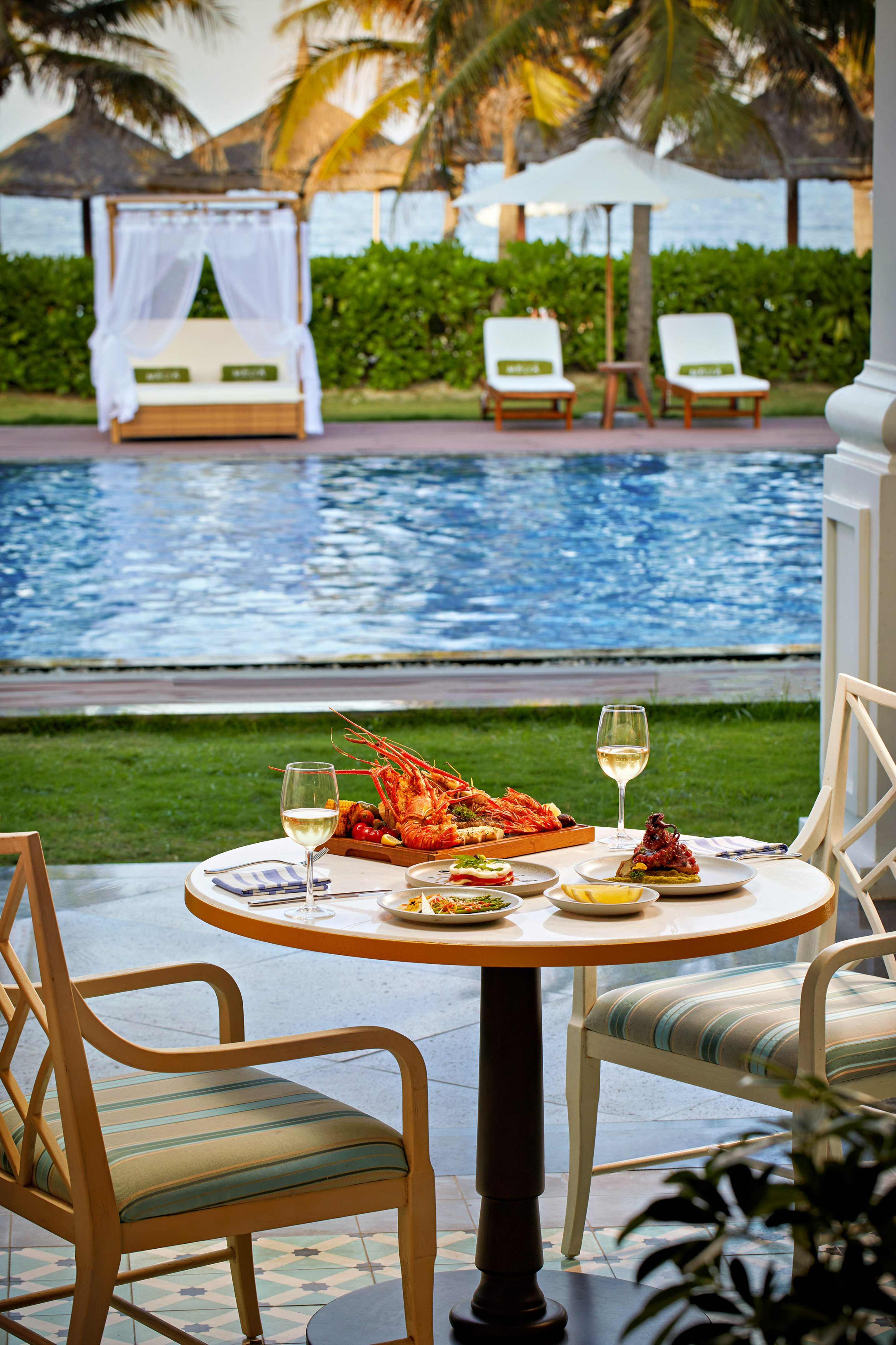 a table with food and wine glasses on it by a pool
