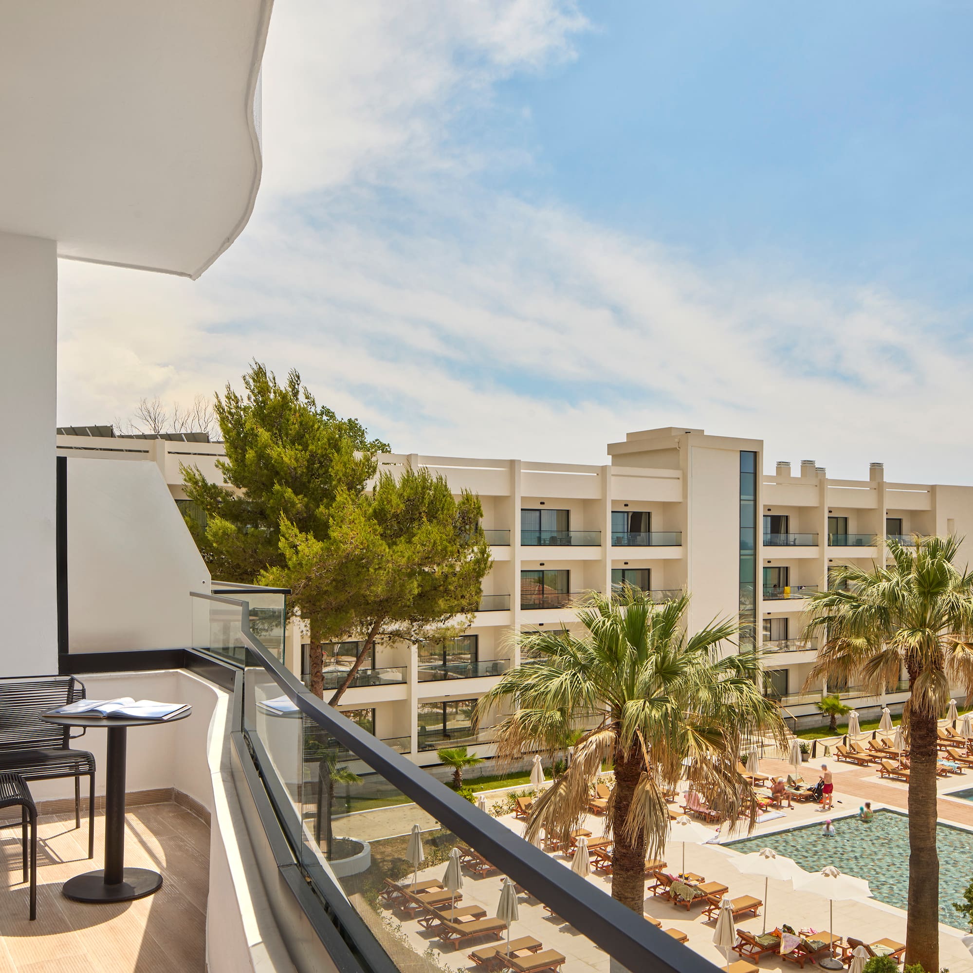 a balcony with chairs and a pool in the background