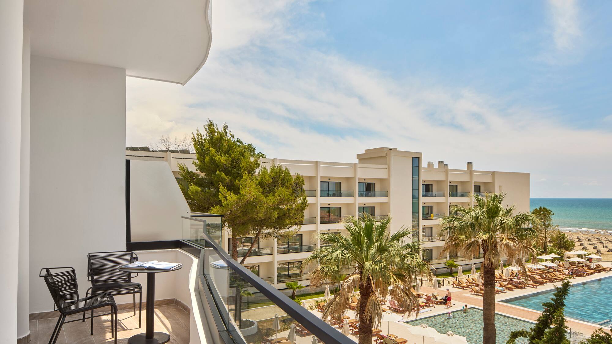 a balcony with chairs and a pool in the background