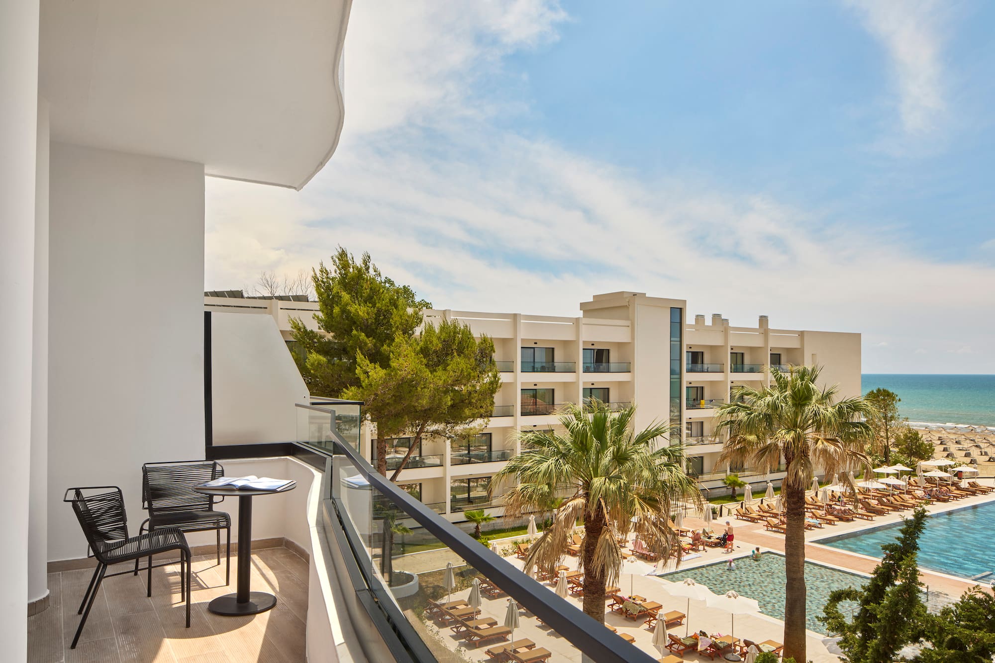 a balcony with chairs and a pool in the background