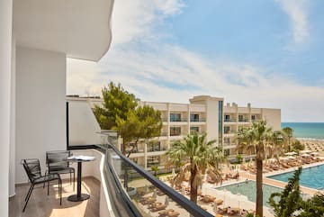 a balcony with chairs and a pool in the background