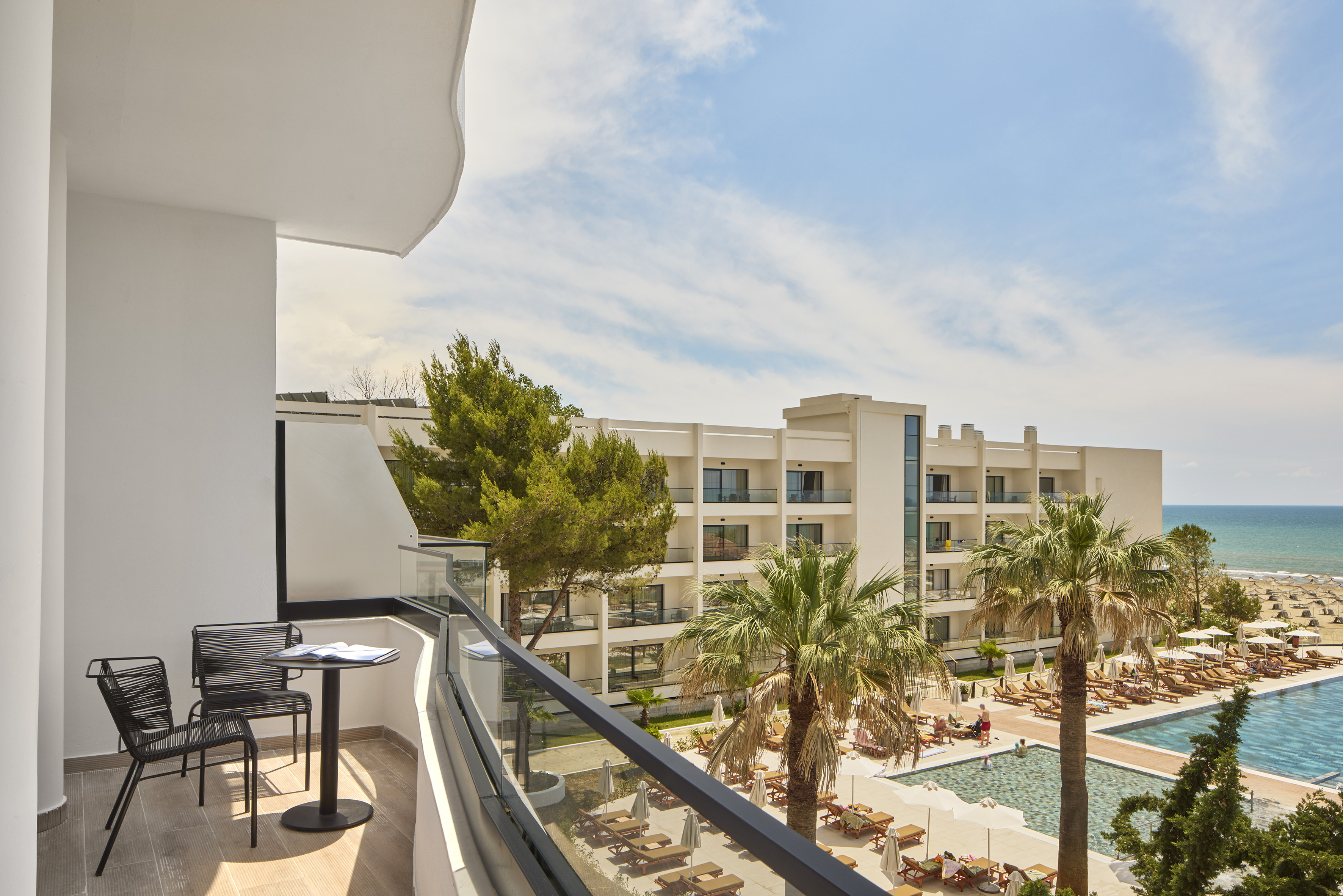 a balcony with chairs and a pool in the background