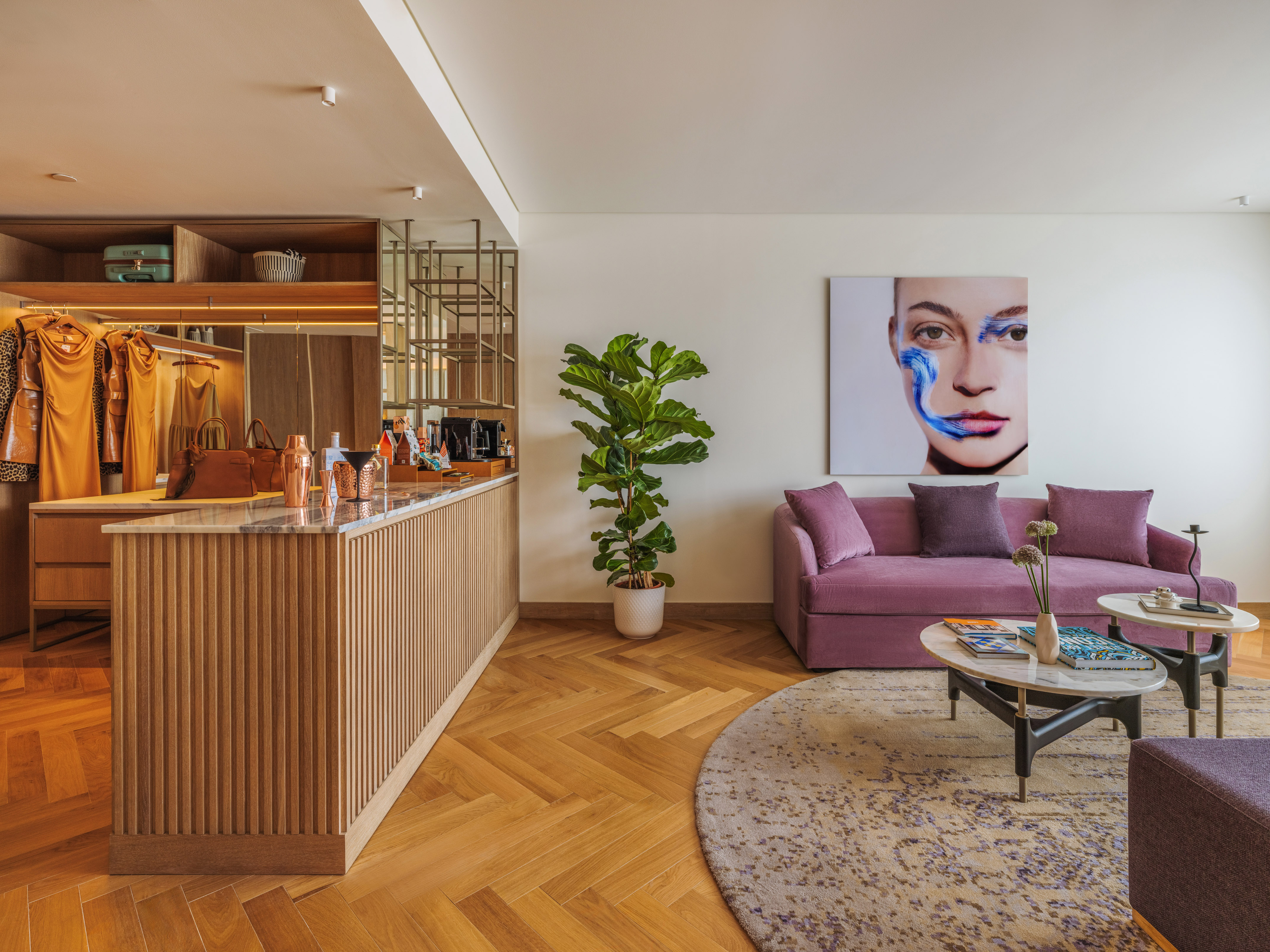 Luxury dressing area, bar, and modern lounge with purple sofa, art.