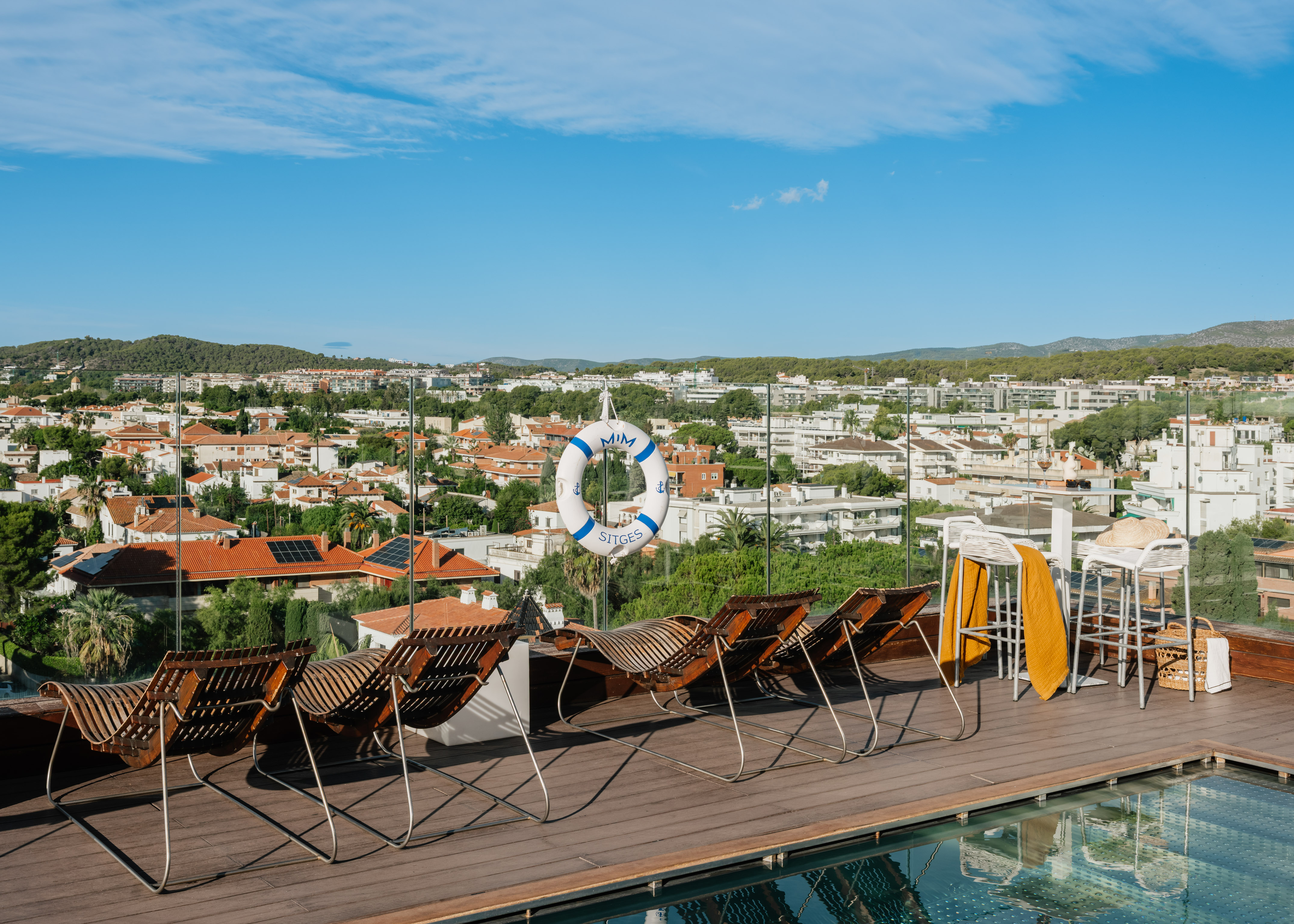 Hotel Mim Sitges rooftop terrace with lounge chairs, pool, and city panorama.