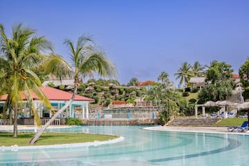 uma piscina com um edifício e palmeiras