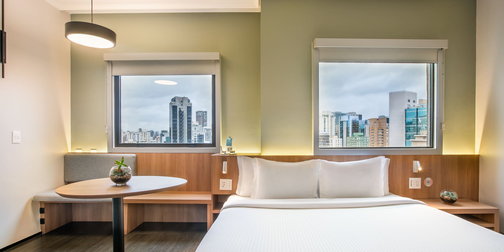 a room with a bed and a table and windows