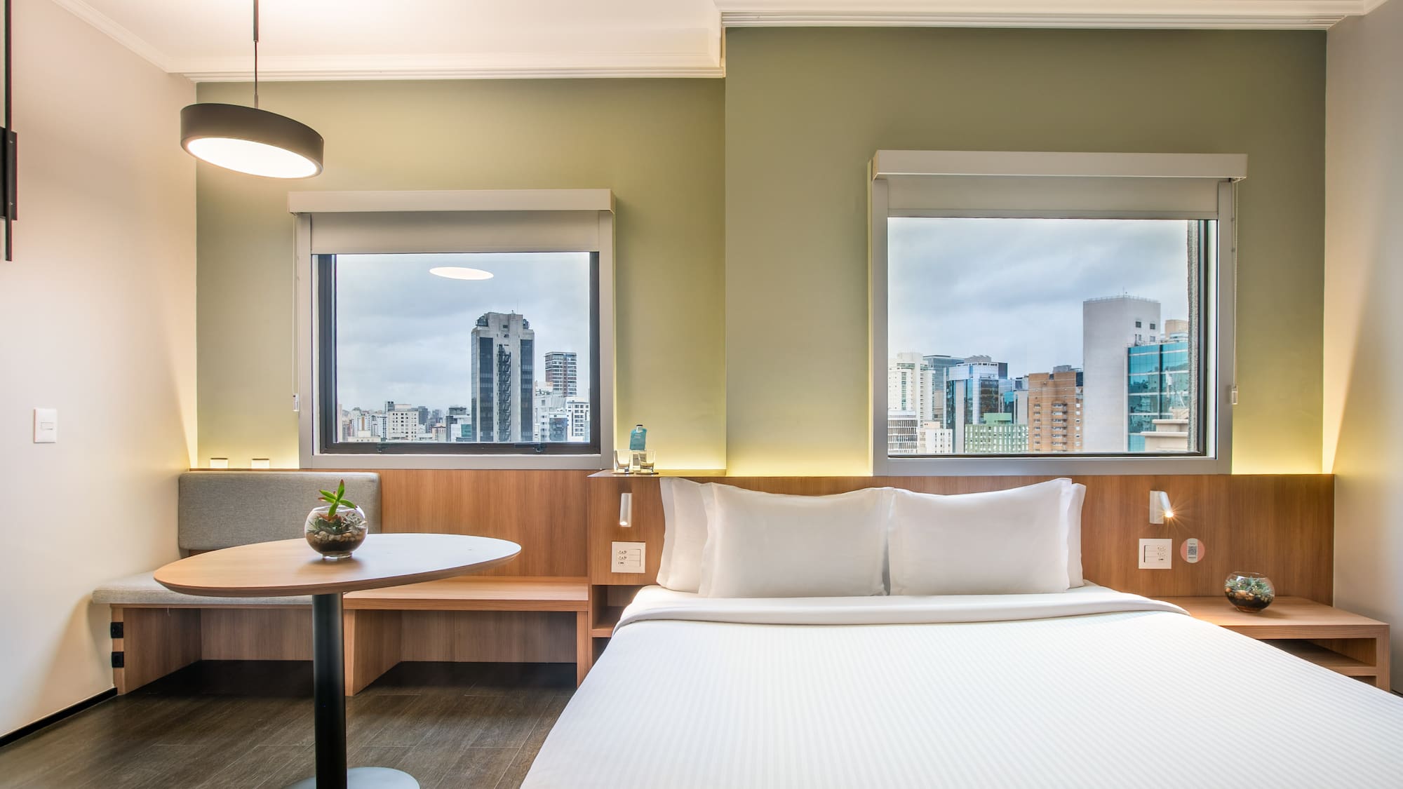 a room with a bed and a table and windows