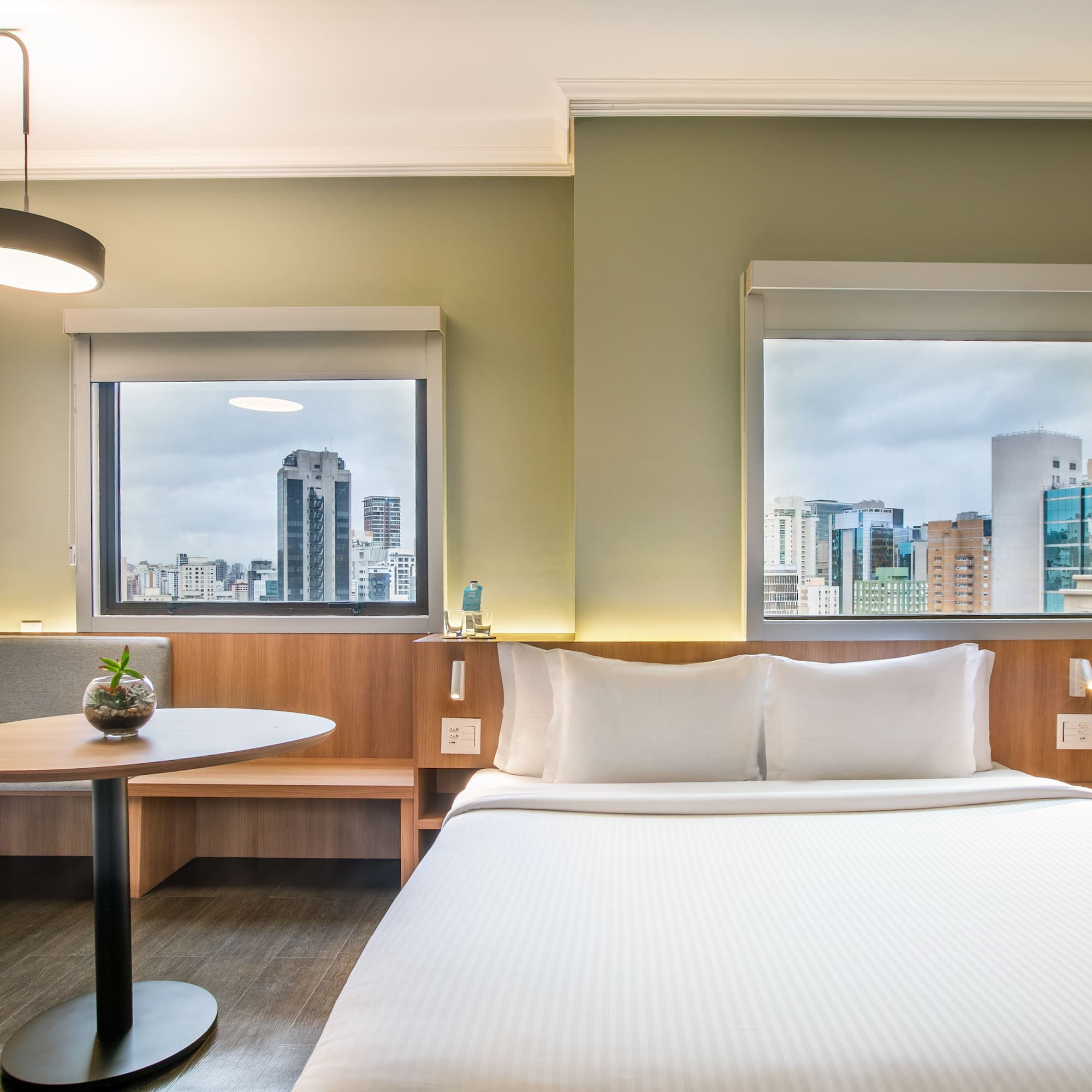 a room with a bed and a table and windows