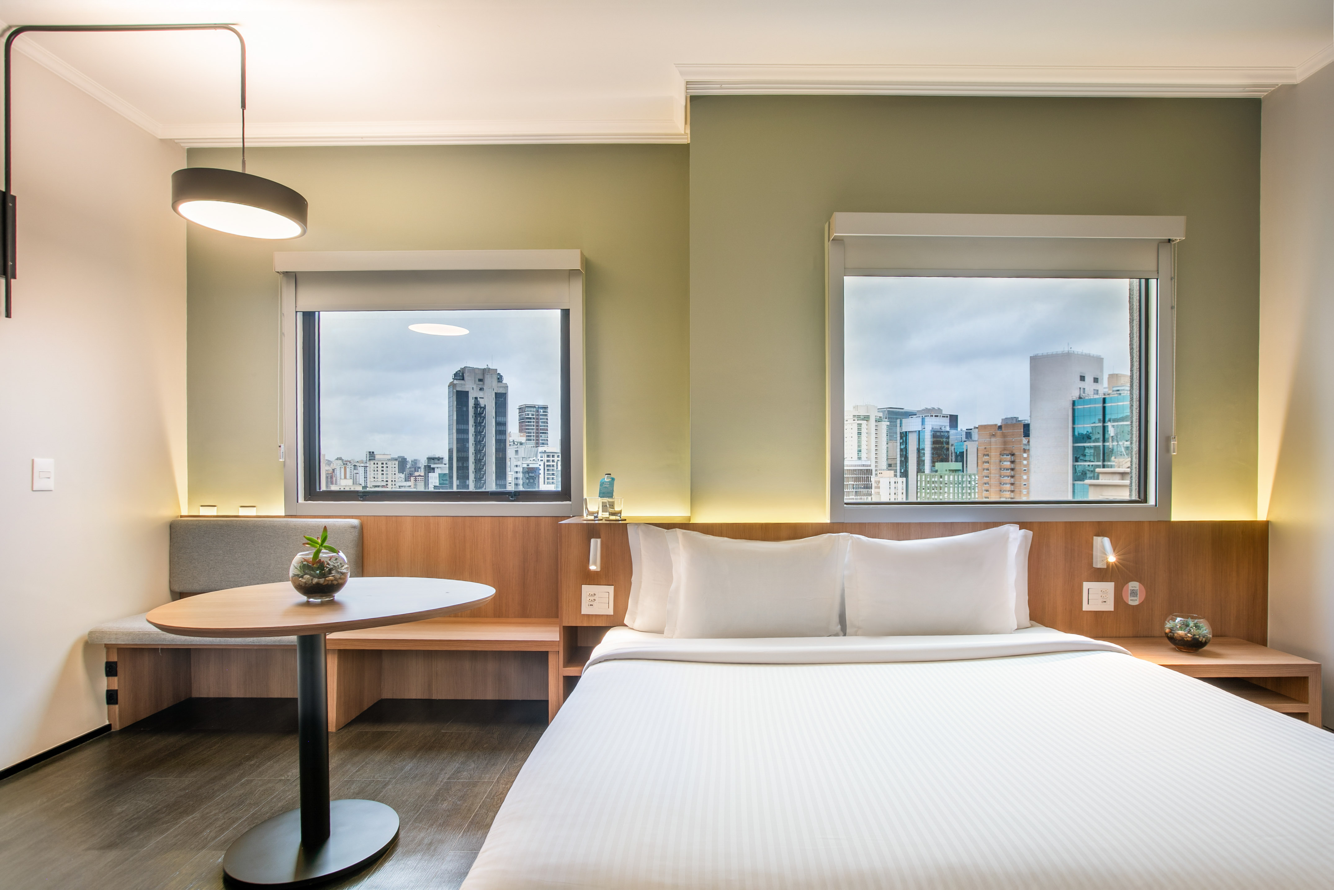 a room with a bed and a table and windows