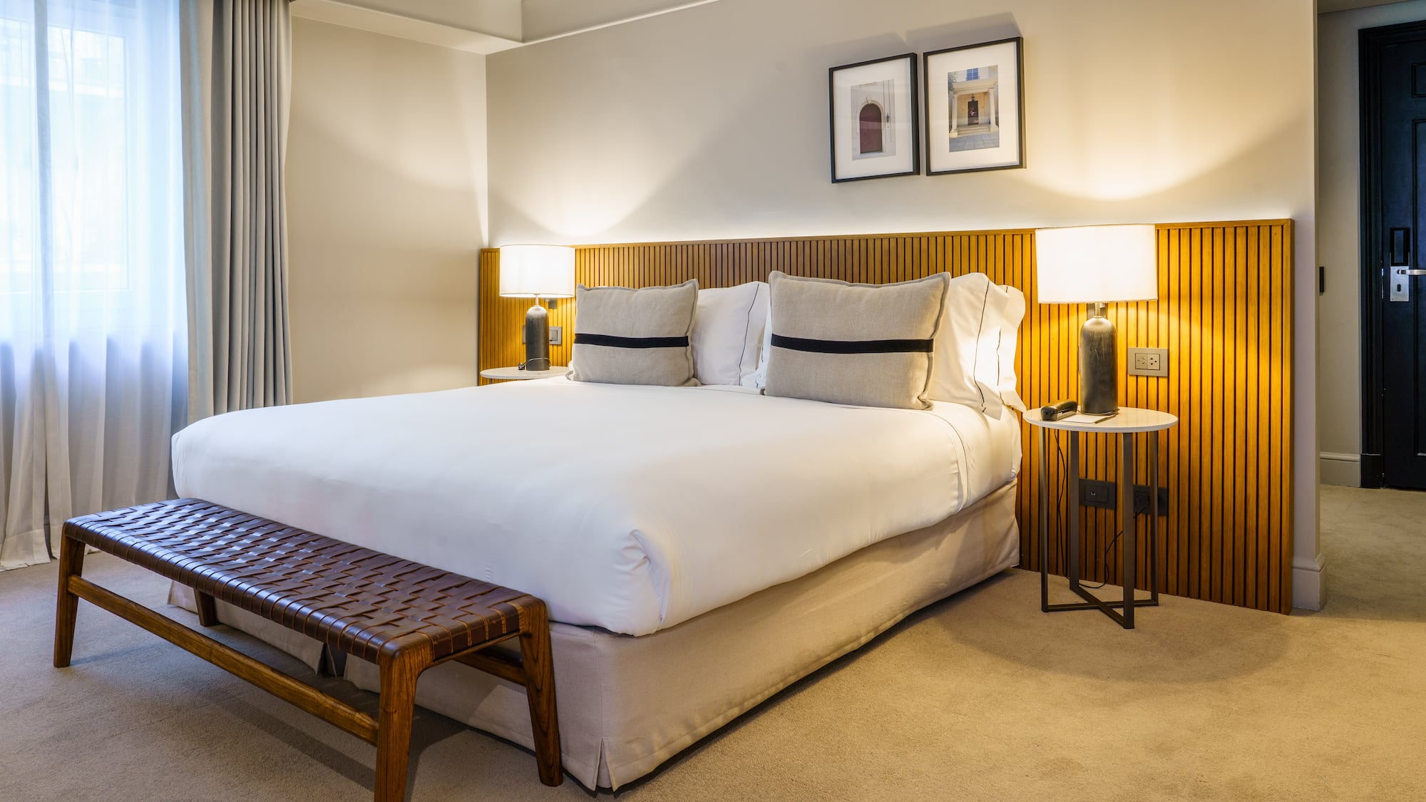 a bed with a bench and lamps in a room
