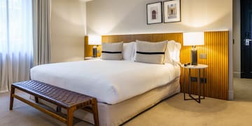 a bed with a bench and lamps in a room