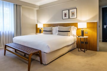 a bed with a bench and lamps in a room