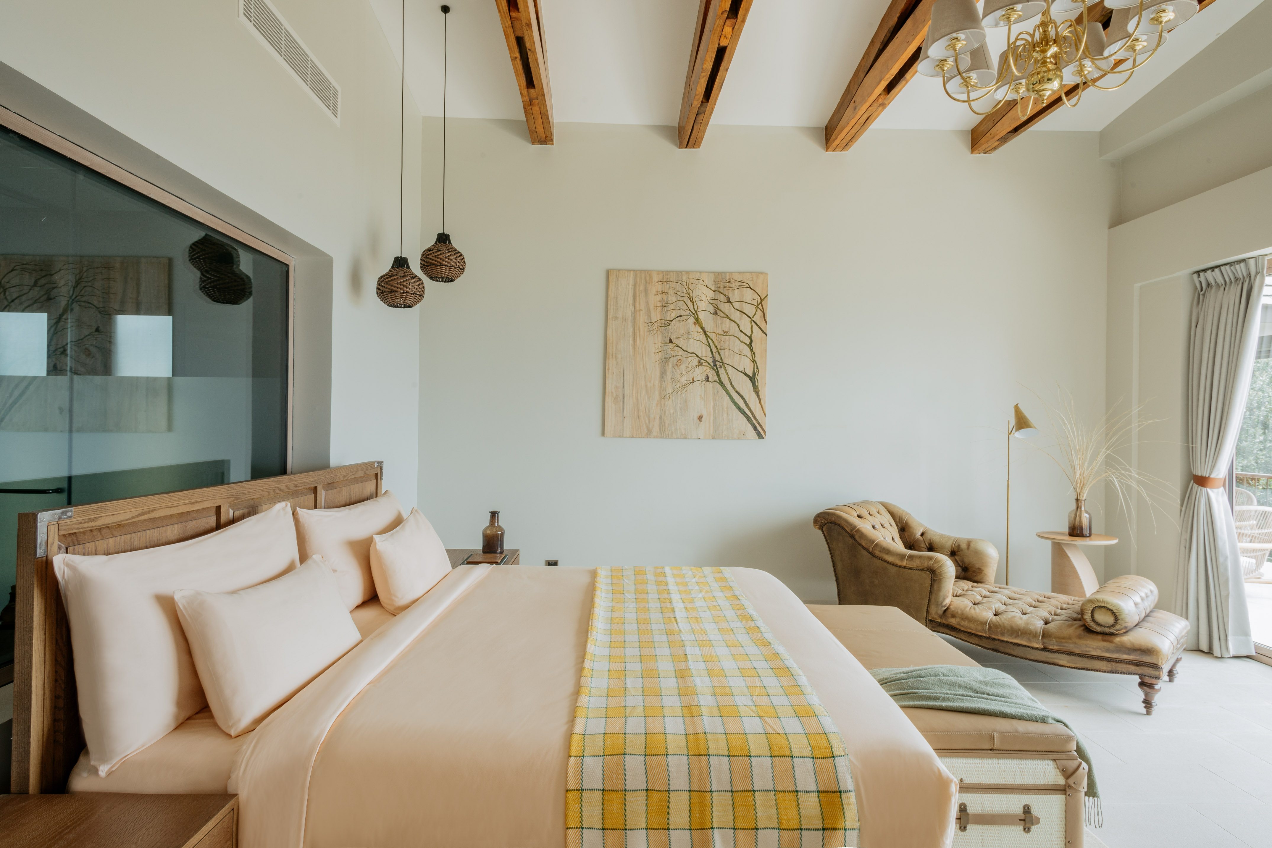 Luxury bedroom with king bed, peach bedding, wooden beams, and a leather chaise.