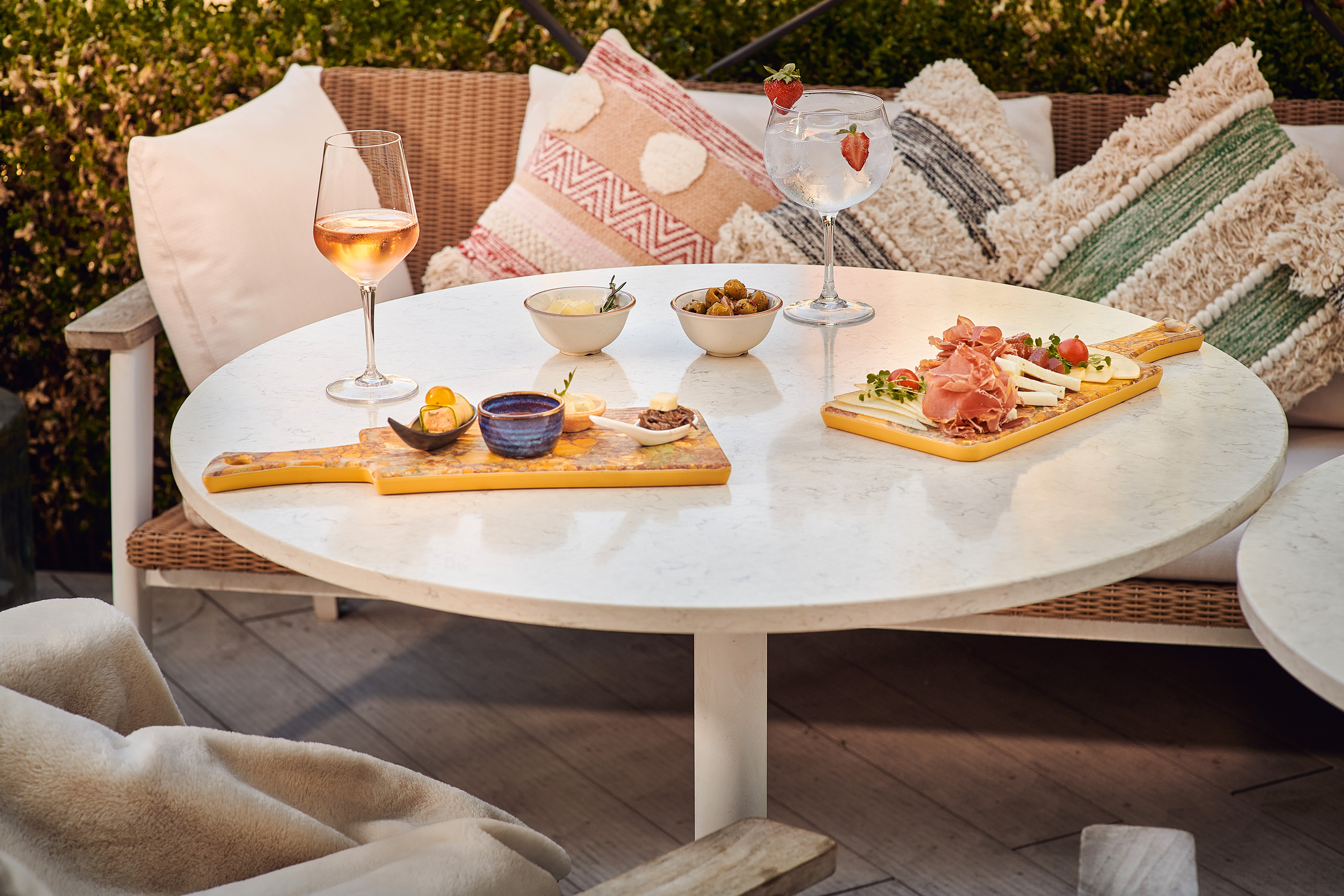 Charcuterie board, rosé, gin, and appetizers on an outdoor patio table.