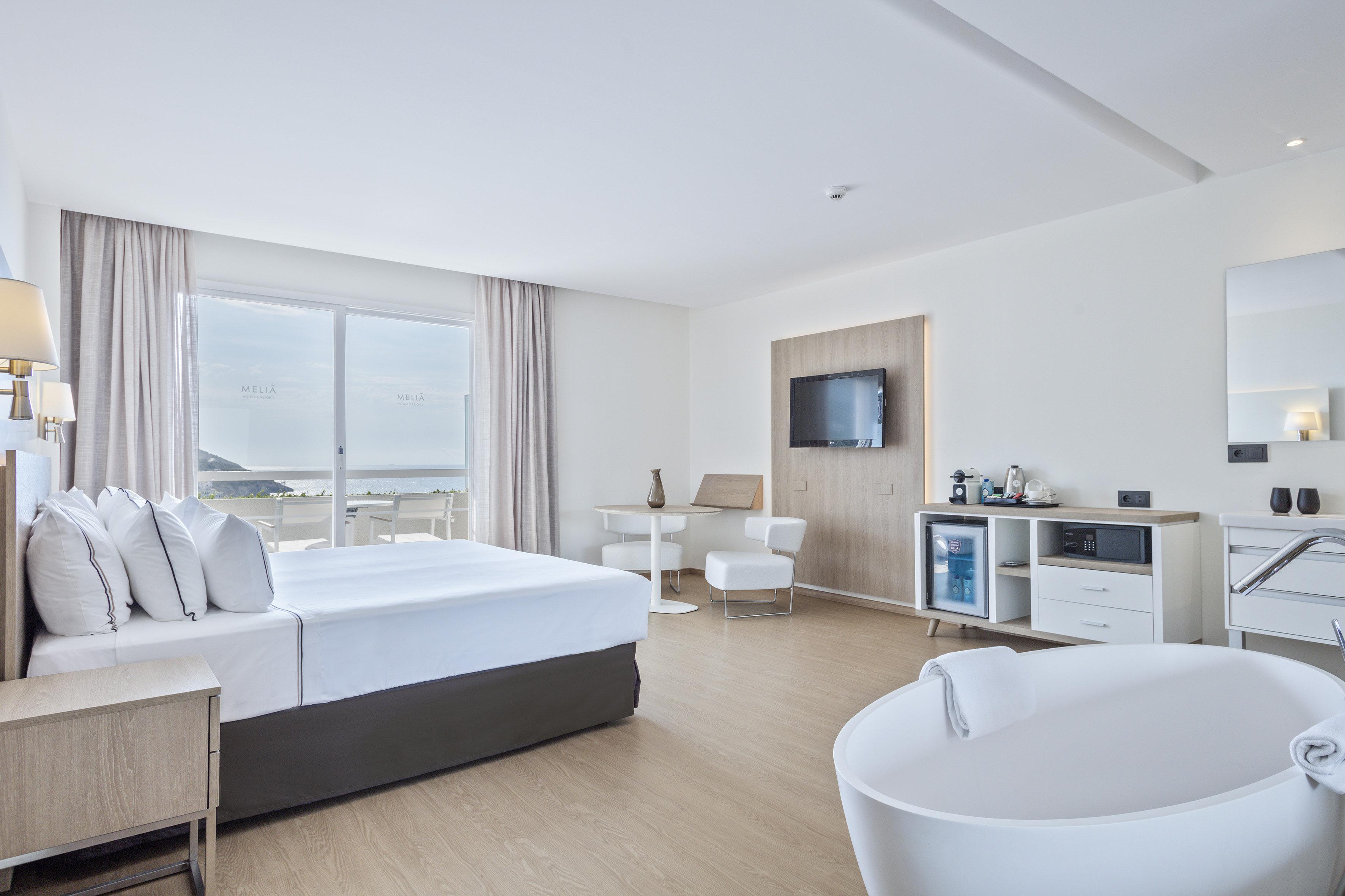 Meliá hotel suite with ocean view balcony, king bed, modern TV, and bathtub.