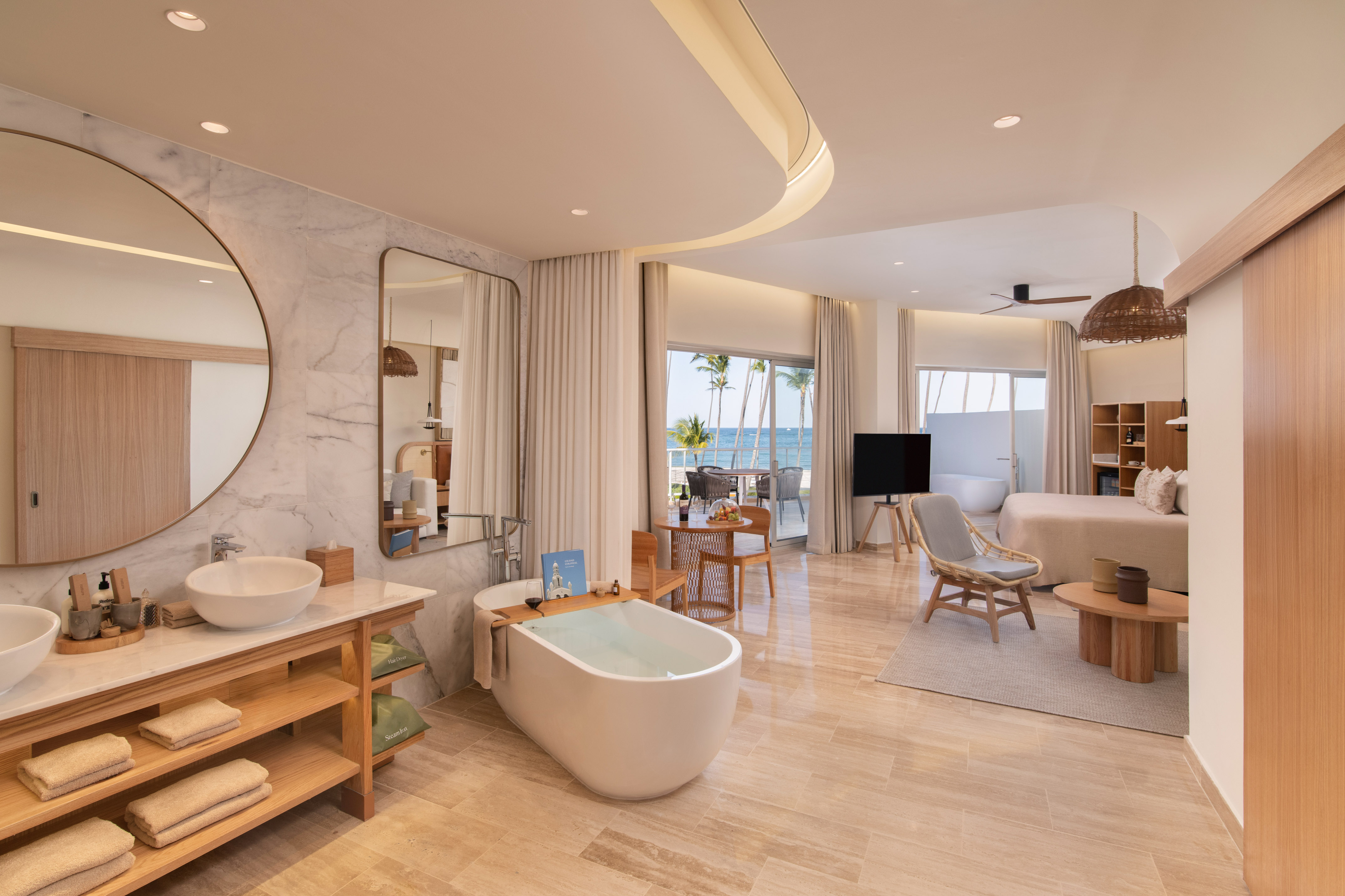 Modern luxury ocean view suite with freestanding tub, marble bathroom, and balcony.