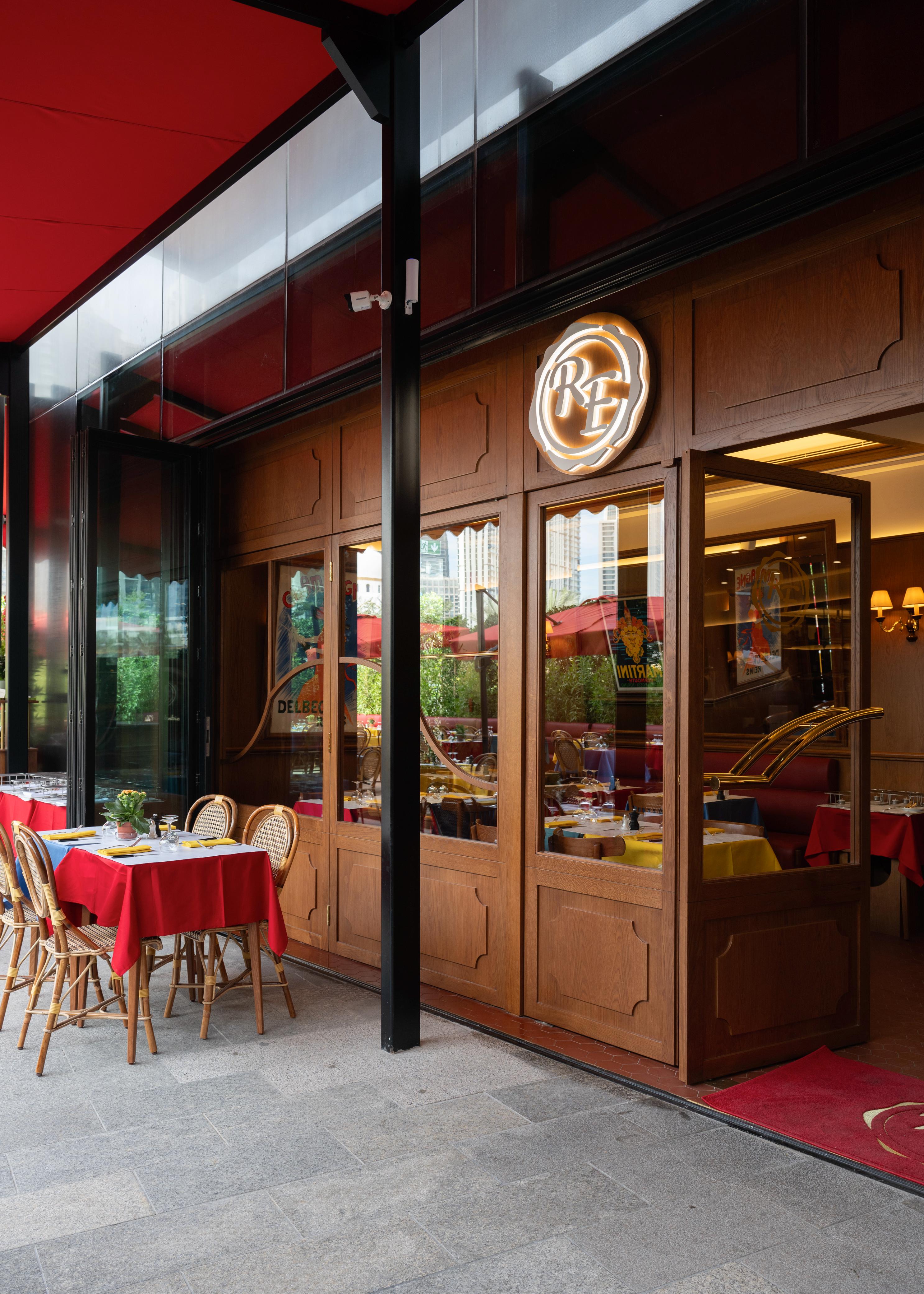 Restaurant exterior with red awning, RF sign, wooden facade, and patio tables.