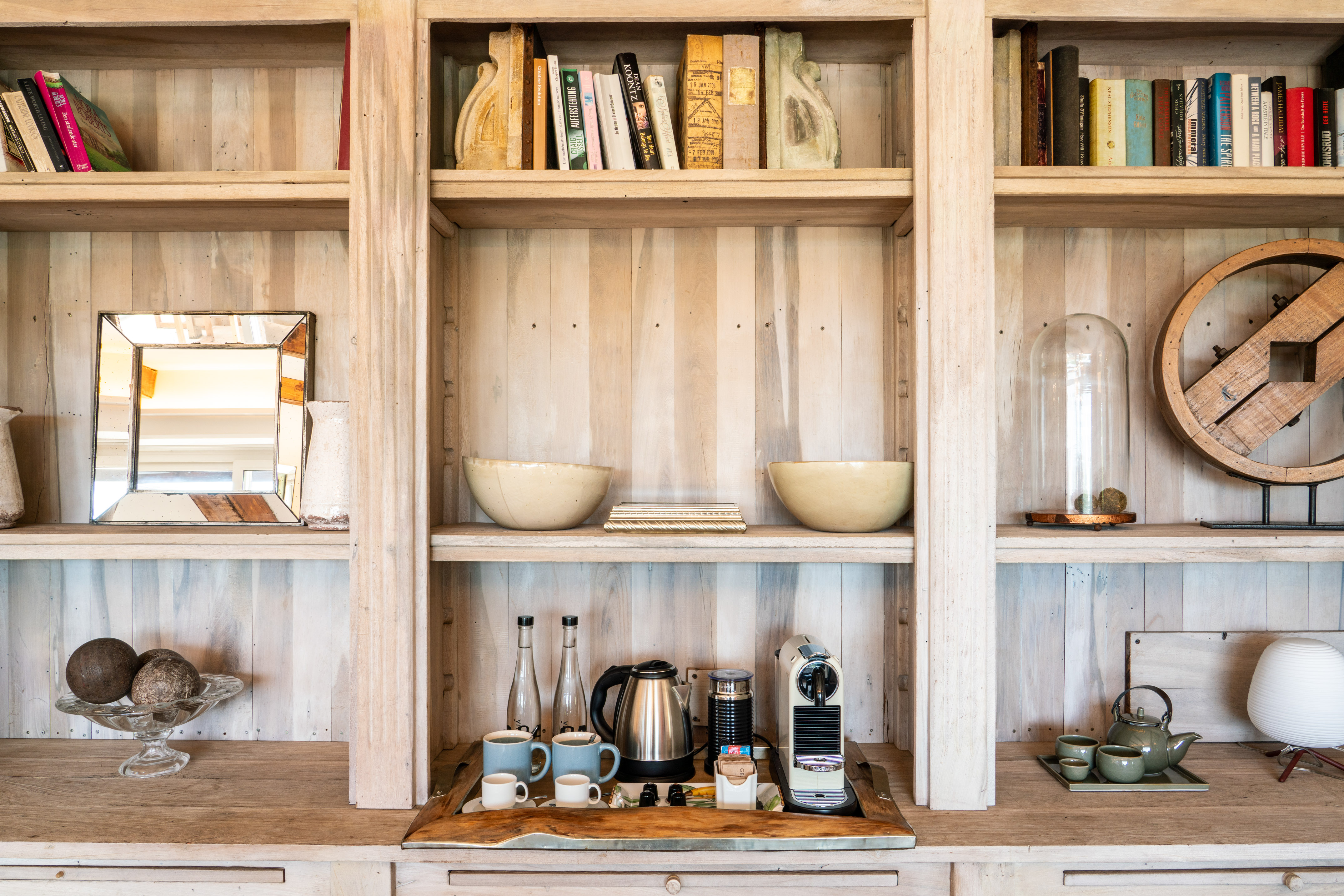 Whitewashed wood bookshelf with coffee station, tea set, books, and decor.
