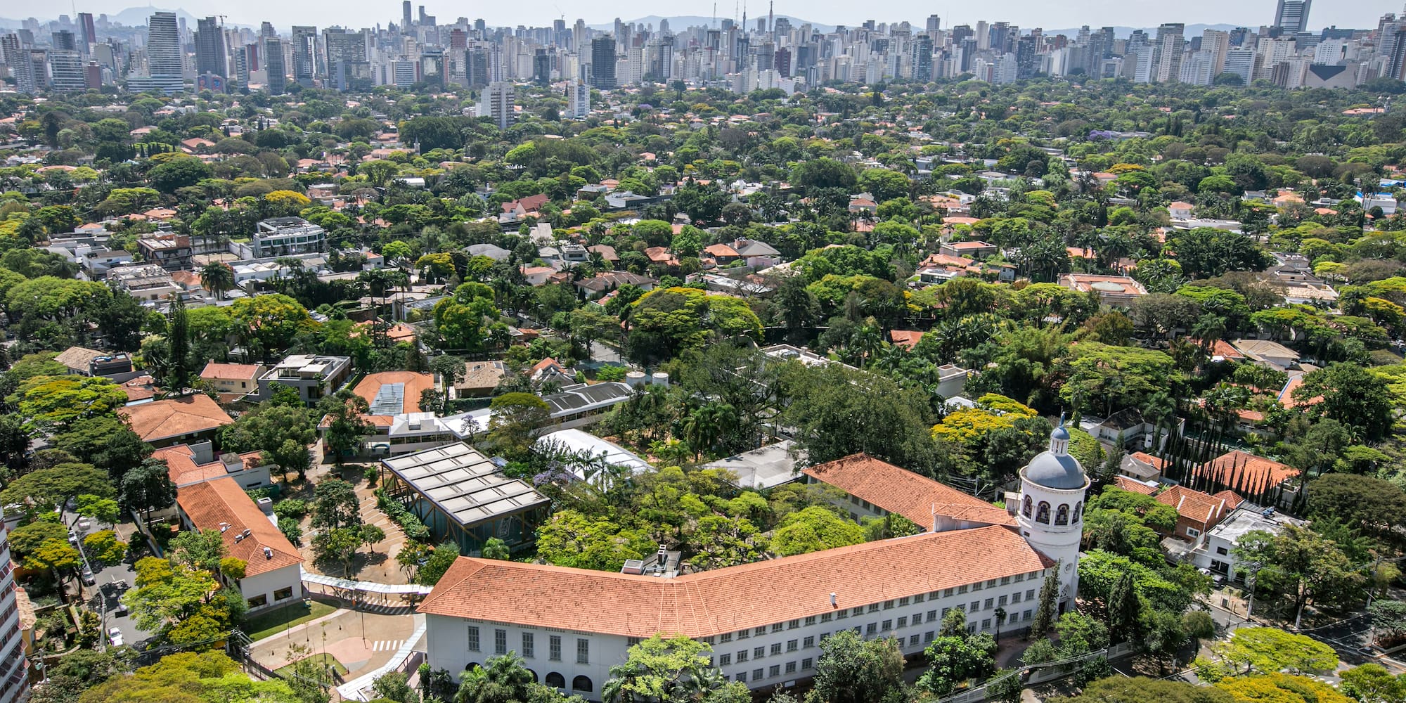 a large building with trees and a city in the background