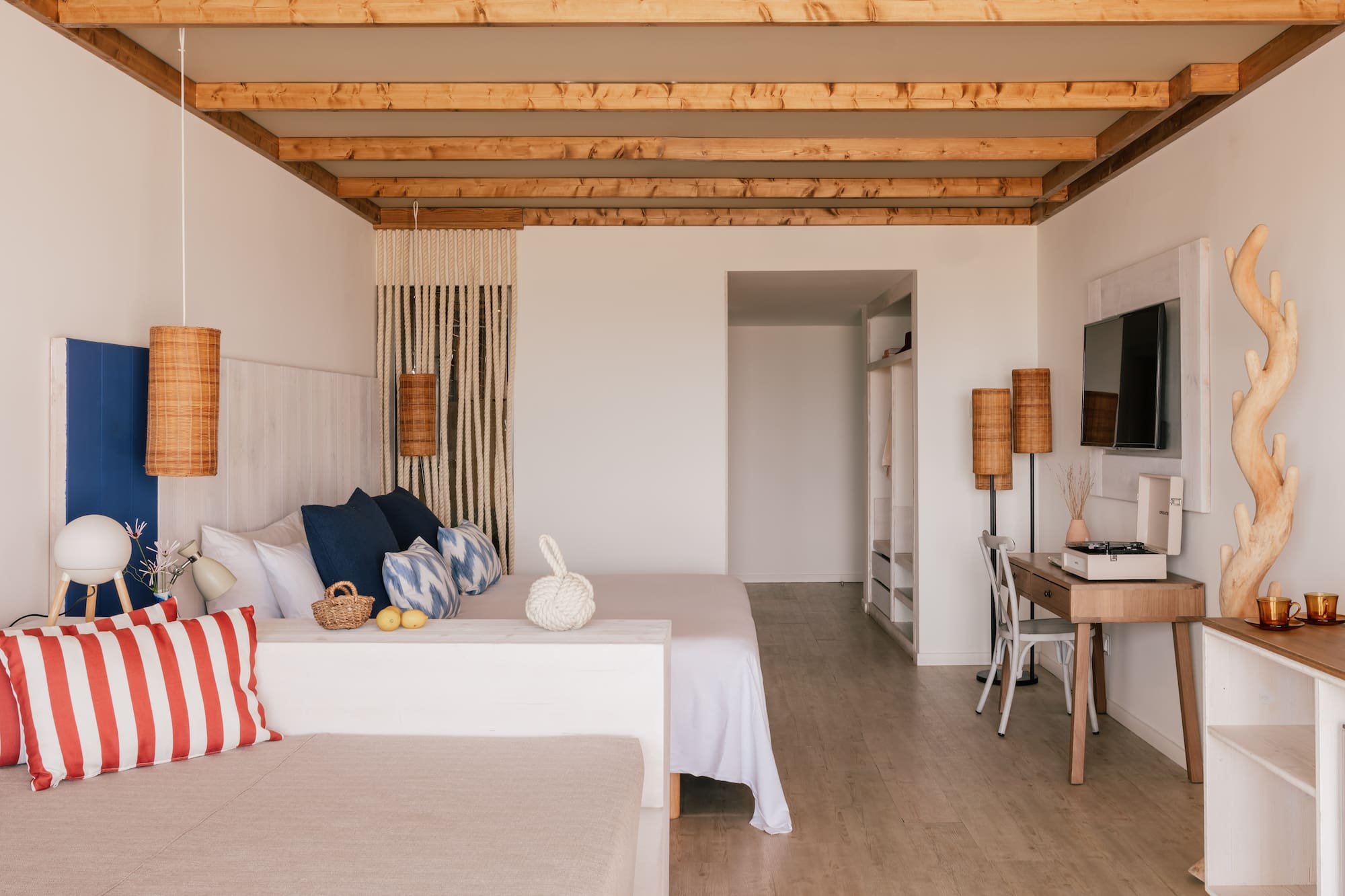 Modern coastal bedroom with wooden ceiling beams and crisp white decor.