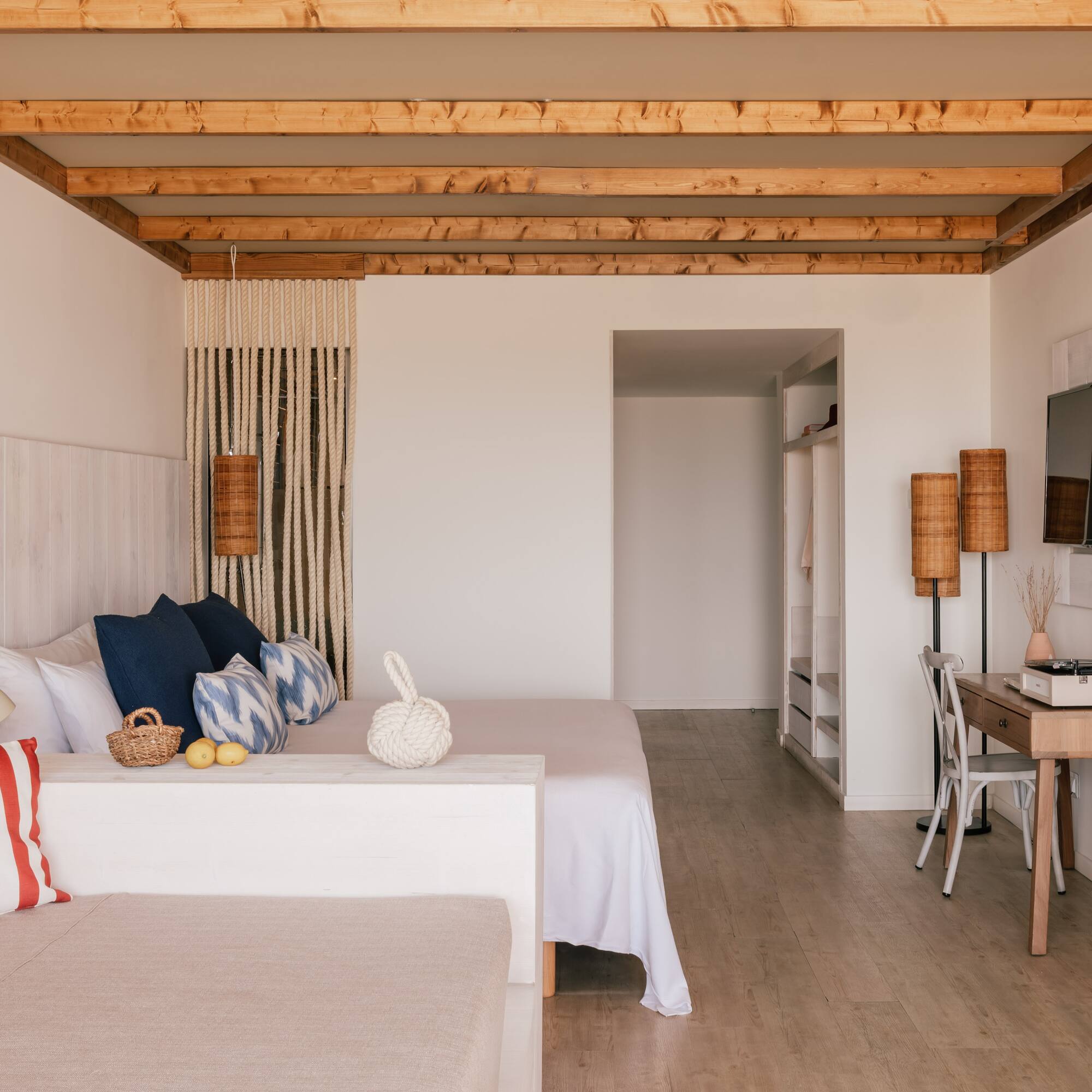 Modern coastal bedroom with wooden ceiling beams and crisp white decor.