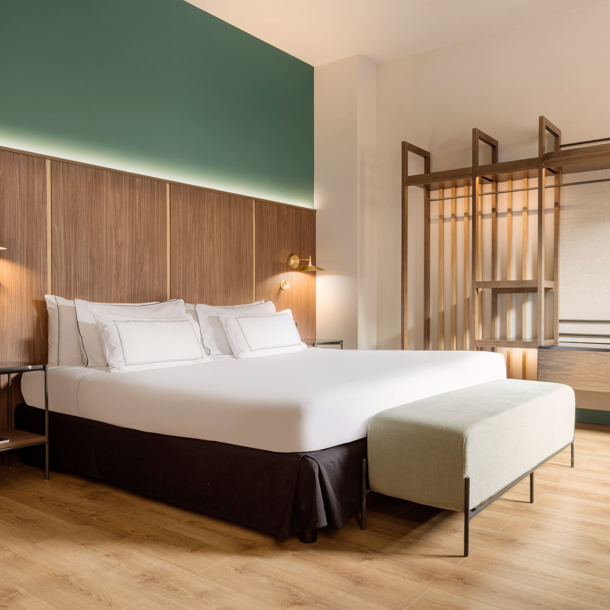 a bed with white sheets and a bench in a room