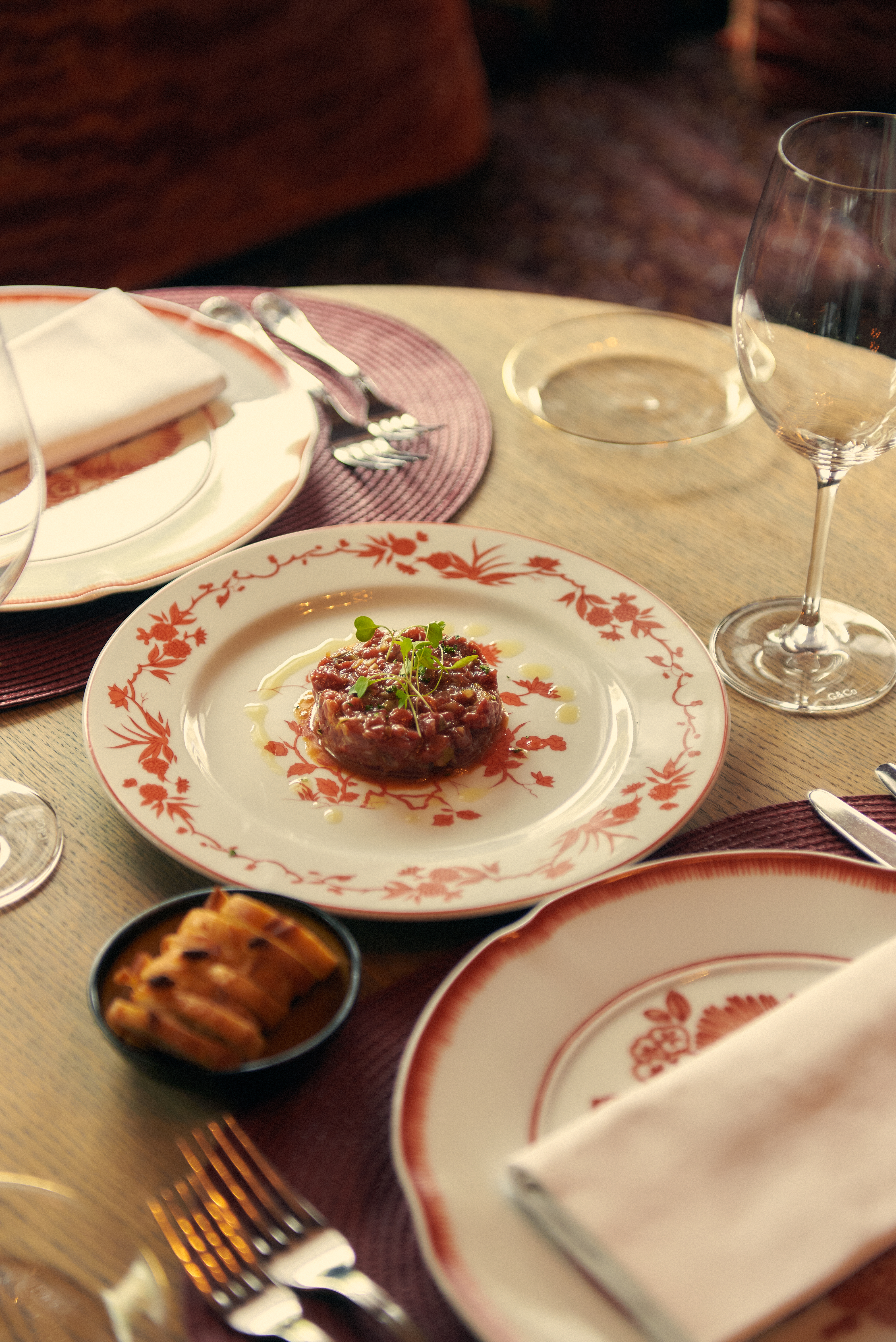 Beef tartare, microgreens, olive oil on decorative plate with bread.