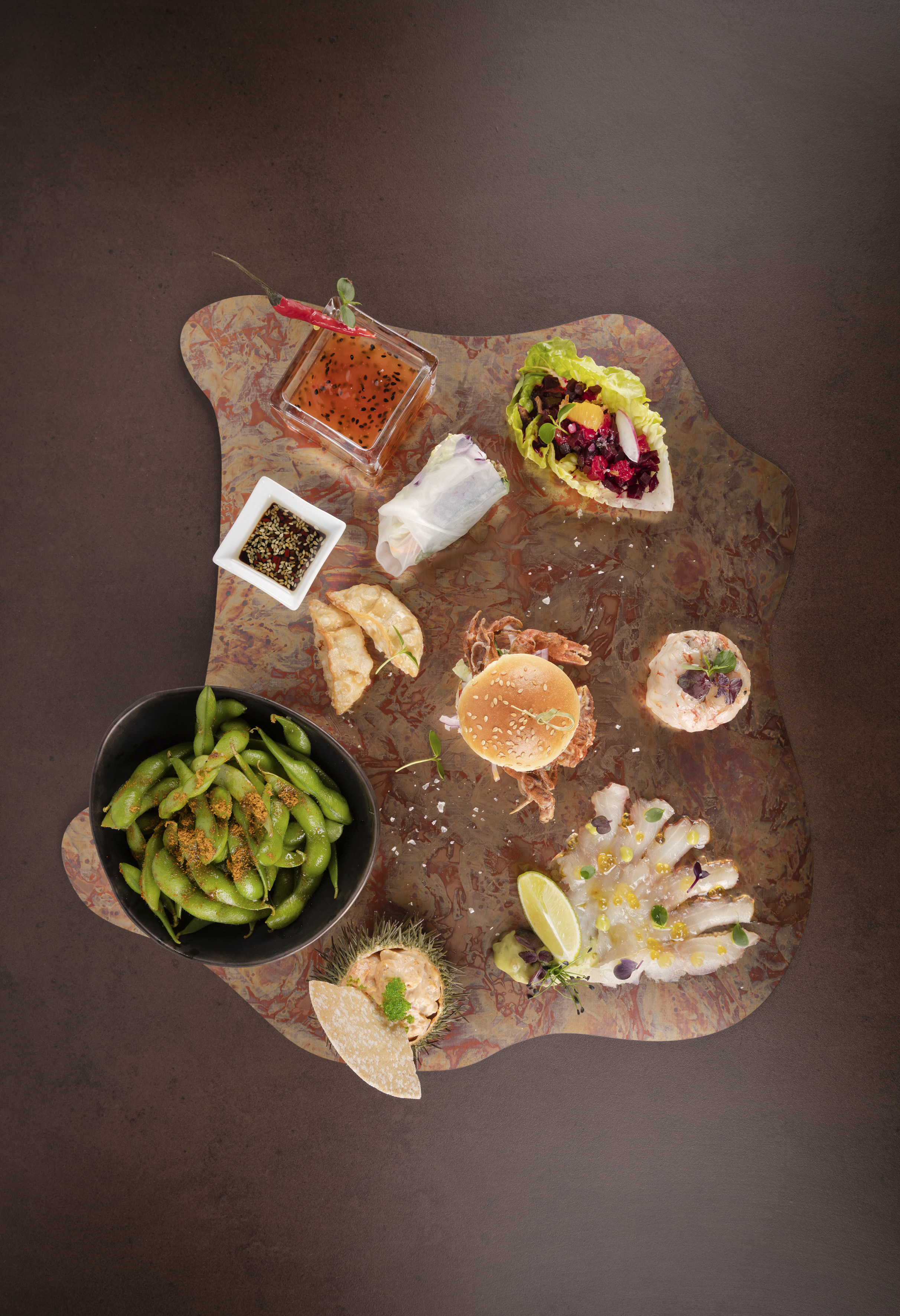 Asian tapas platter: edamame, soft-shell crab, sashimi, spring rolls, dumplings, sauces.