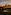 Black helicopter parked at luxury resort restaurant during golden sunset.
