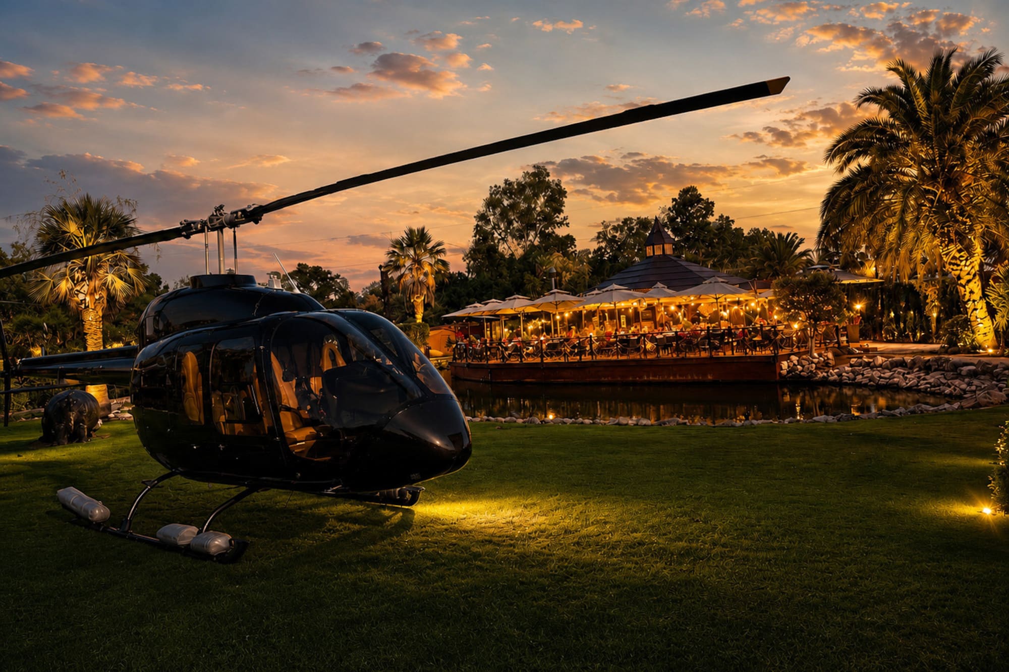 Black helicopter parked at luxury resort restaurant during golden sunset.