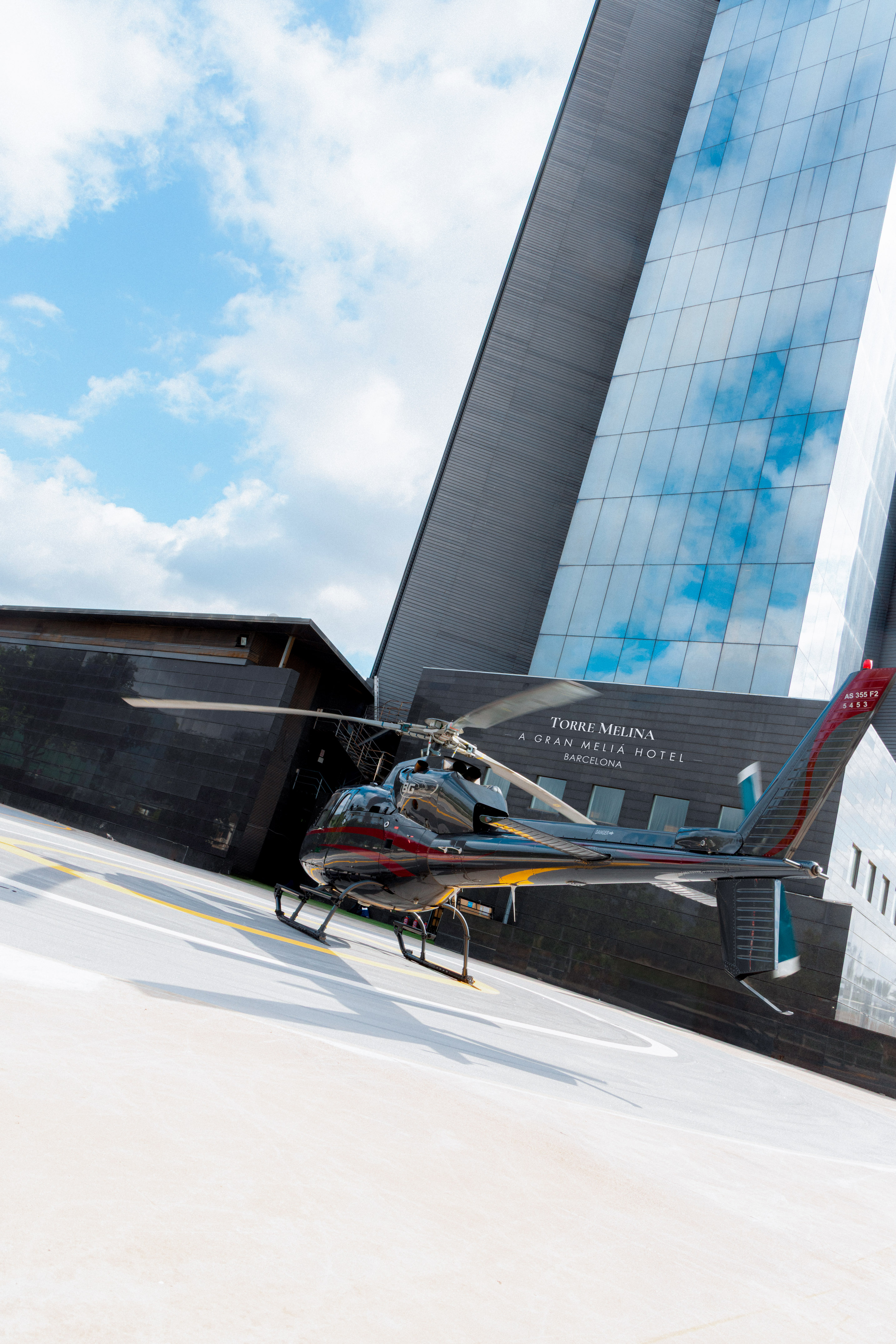 Black helicopter on helipad in front of Torre Melina Hotel, Barcelona.