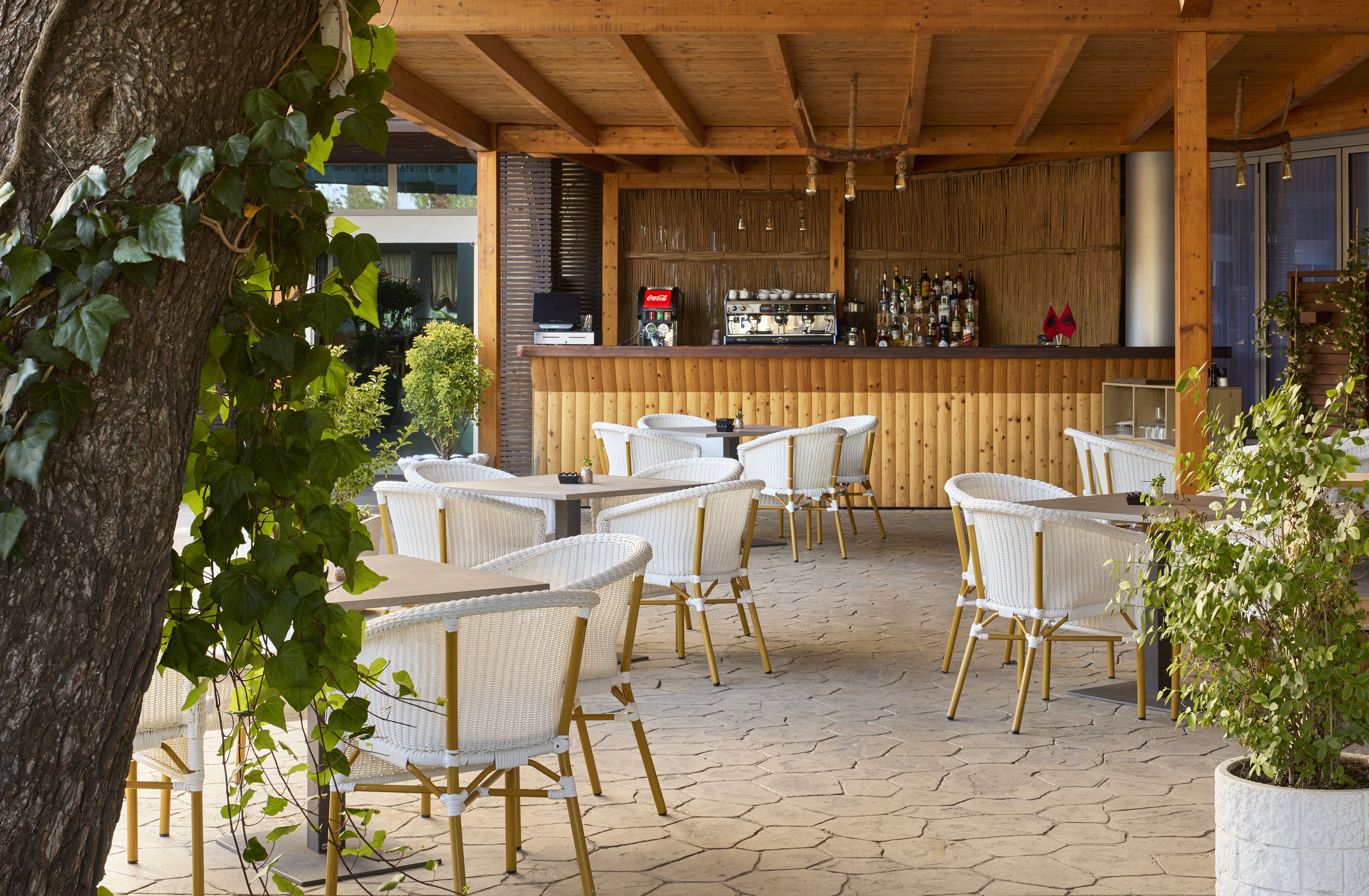 Resort al fresco bar area with white wicker chairs and wooden counter.