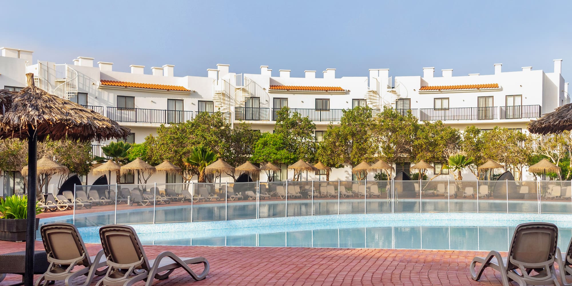 a pool with chairs and trees in the background