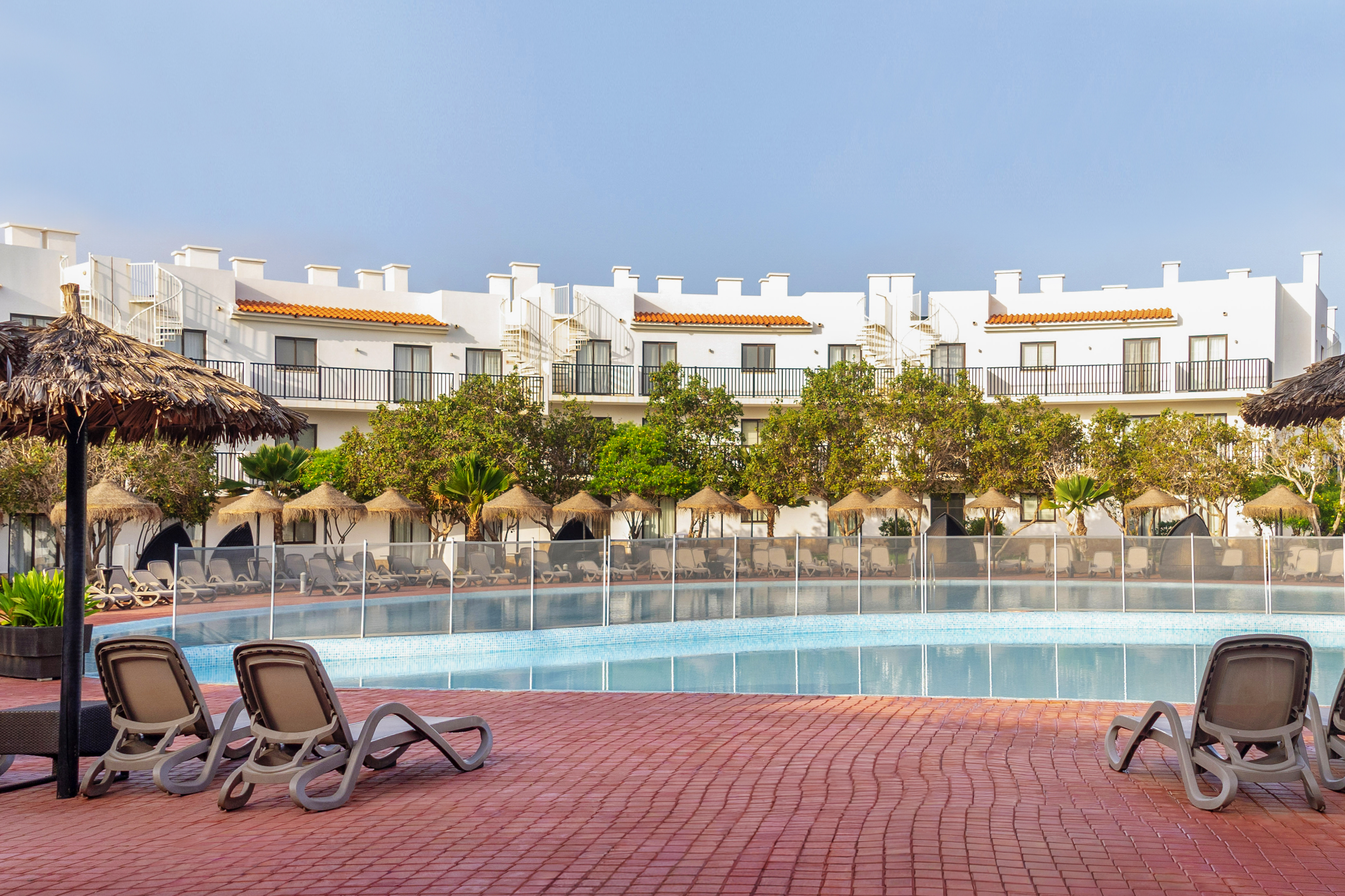 a pool with chairs and trees in the background