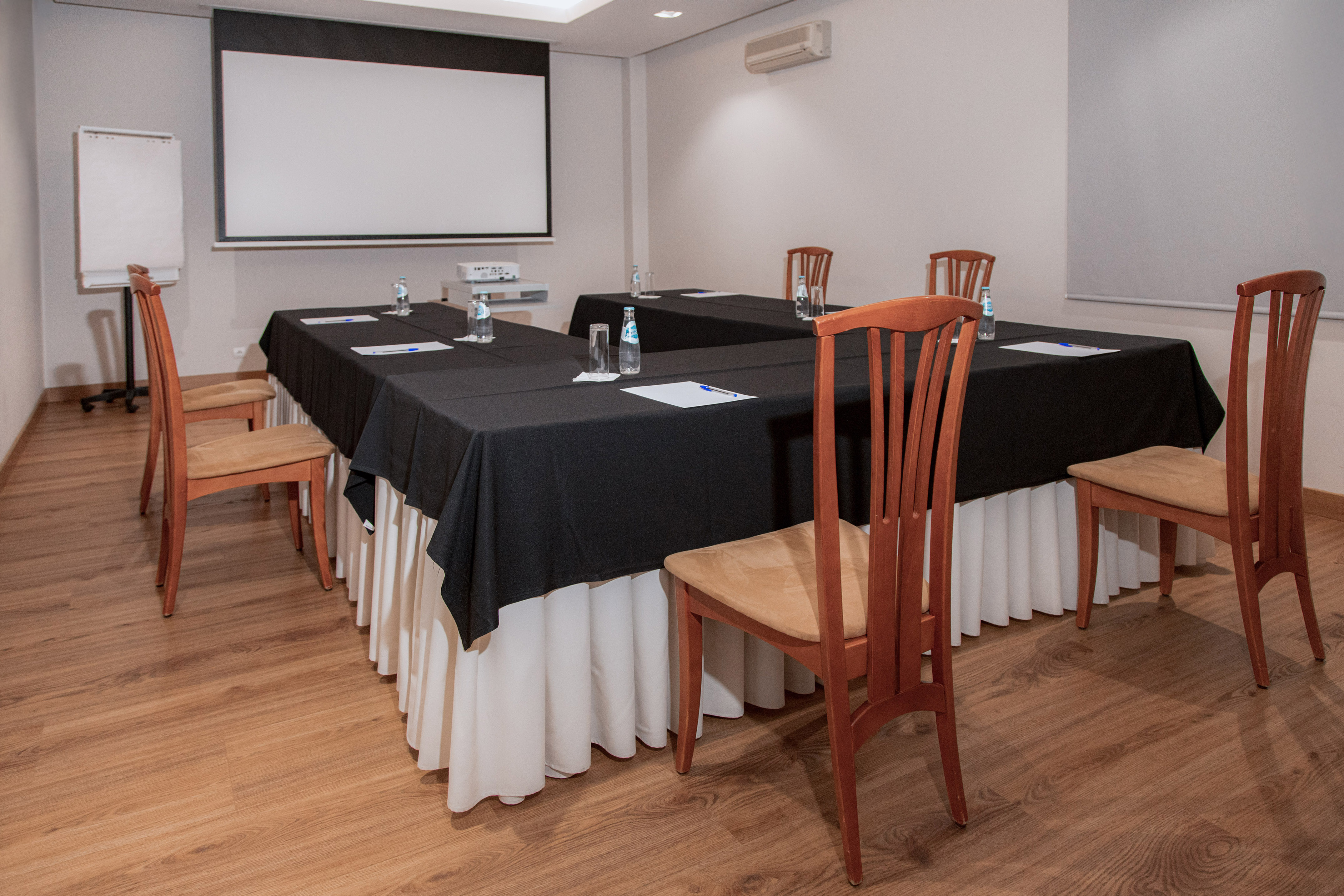 Conference room with tables, chairs, projector screen, and flip chart.