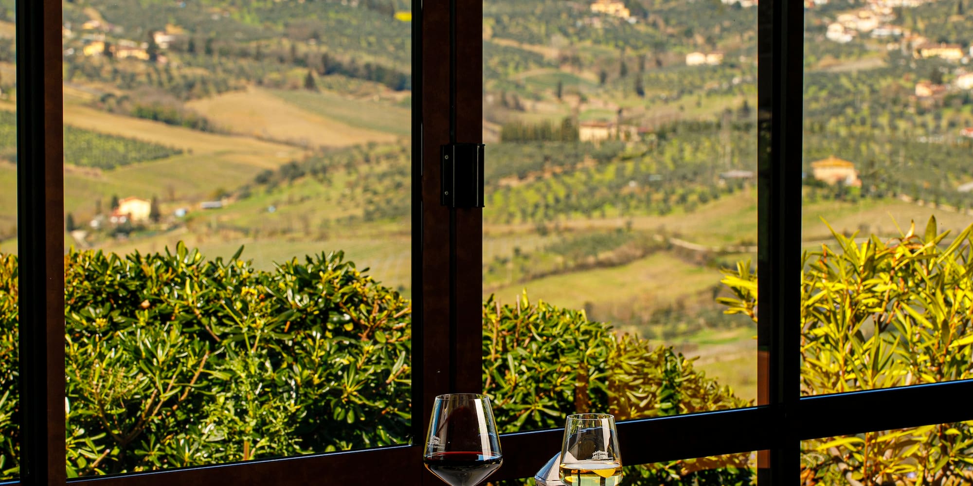 a table with food and glasses on it outside with a view of a valley