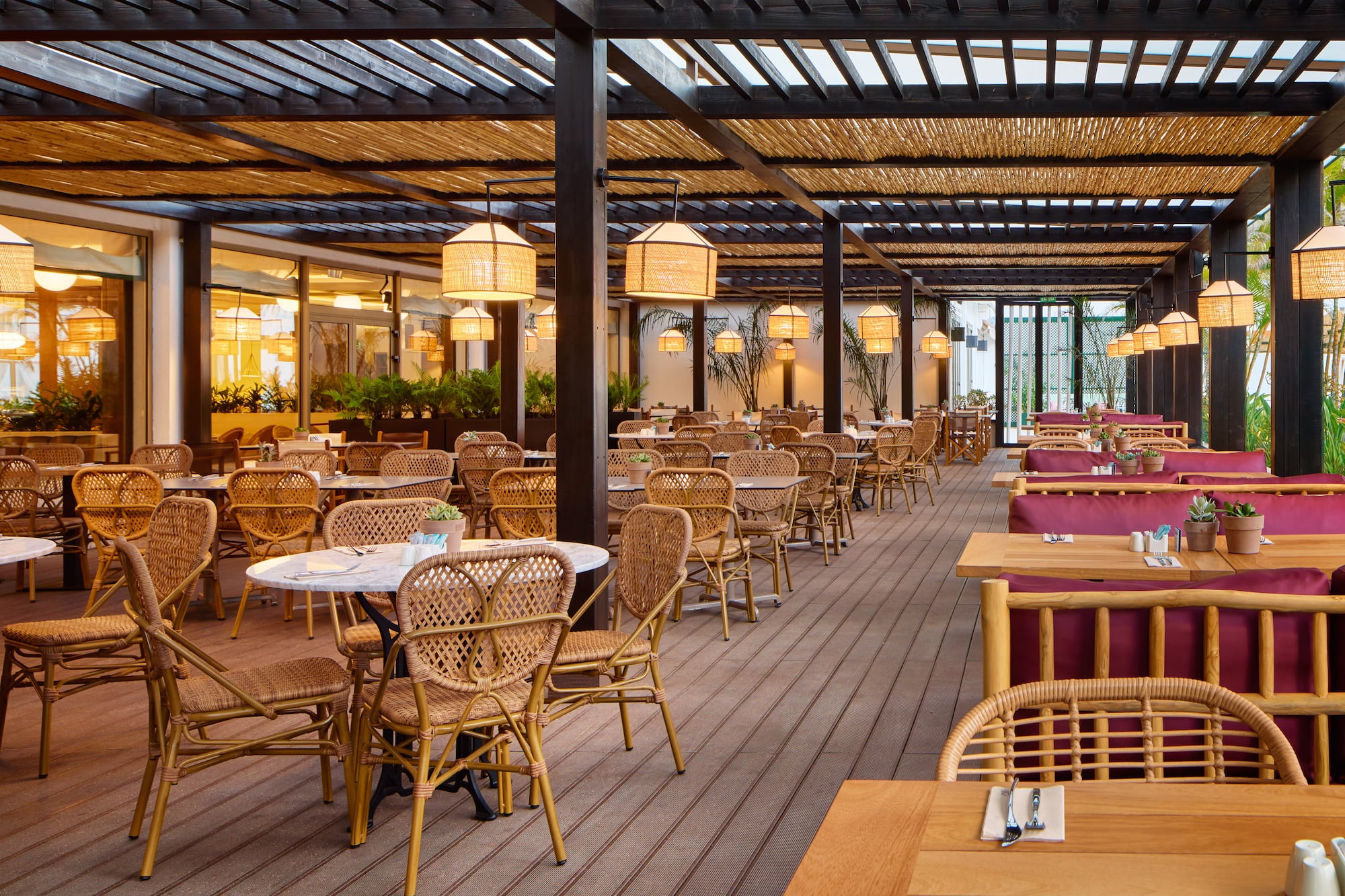 Outdoor restaurant with wicker dining chairs and bamboo pergola.