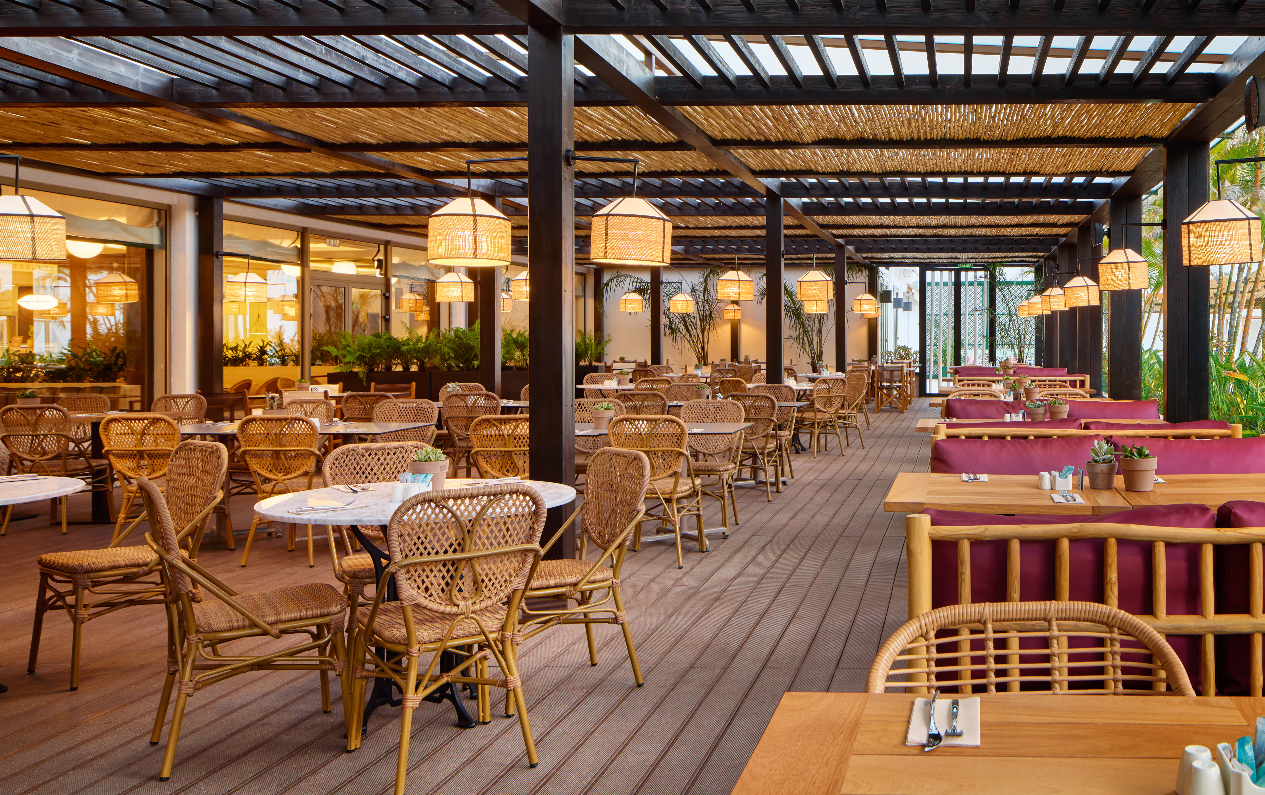 Outdoor restaurant with wicker dining chairs and bamboo pergola.