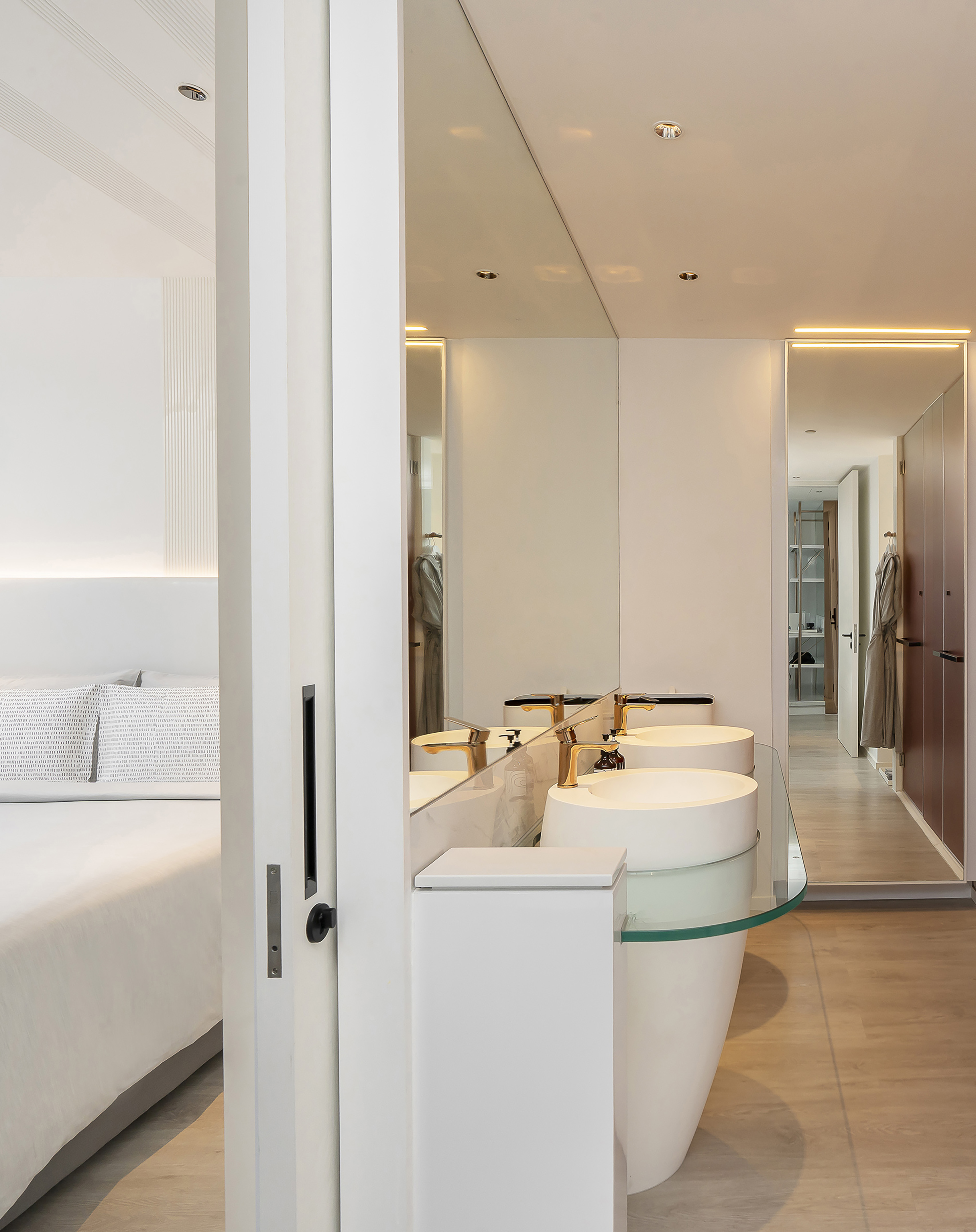 Contemporary ensuite bathroom with double sinks, gold faucets, adjacent to bedroom.