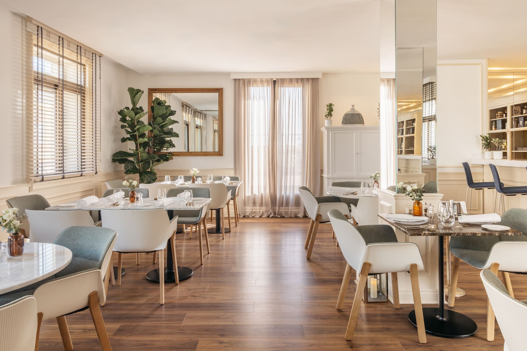 Stylish modern restaurant dining room with set tables, chairs, and wood floor.
