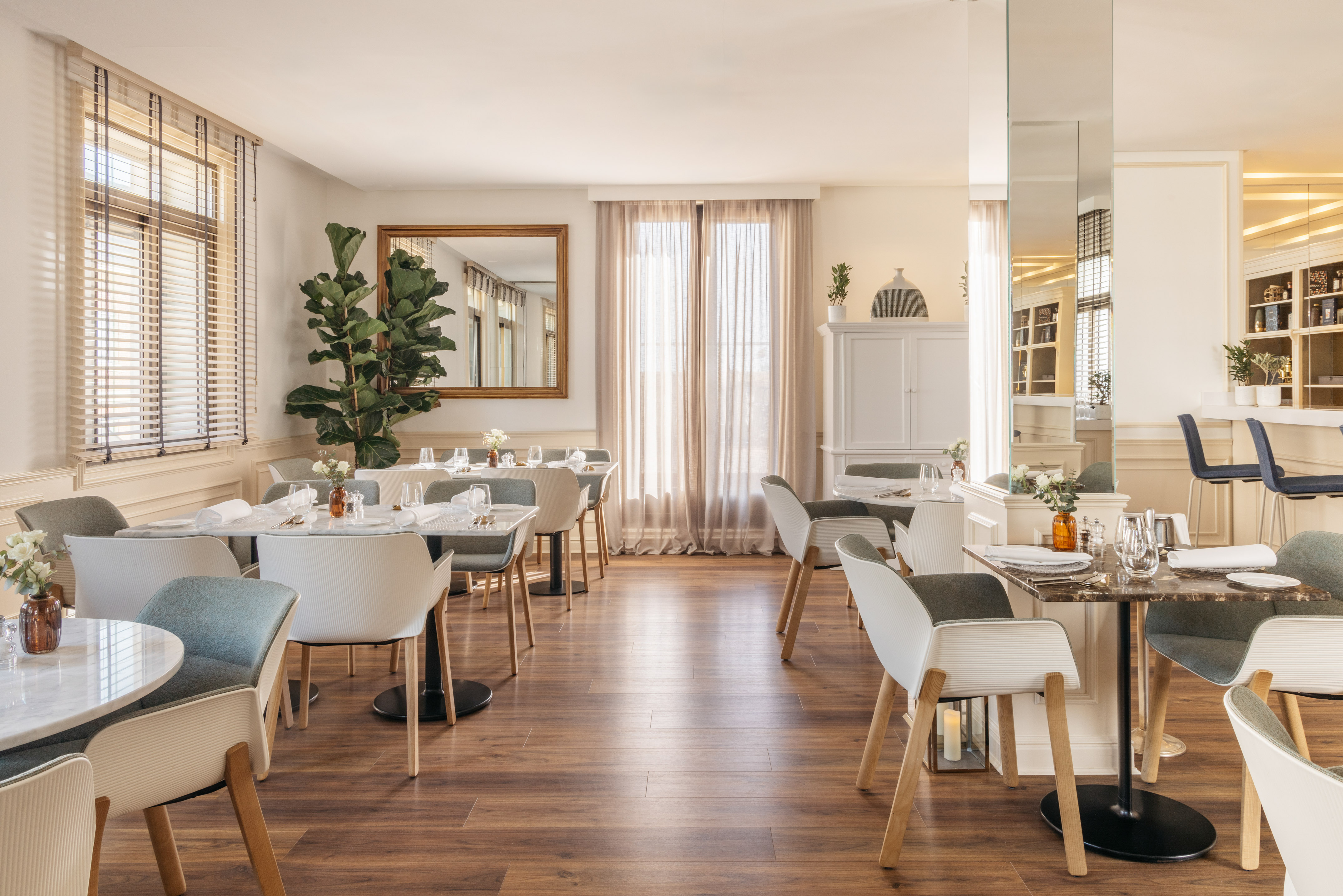 Stylish modern restaurant dining room with set tables, chairs, and wood floor.