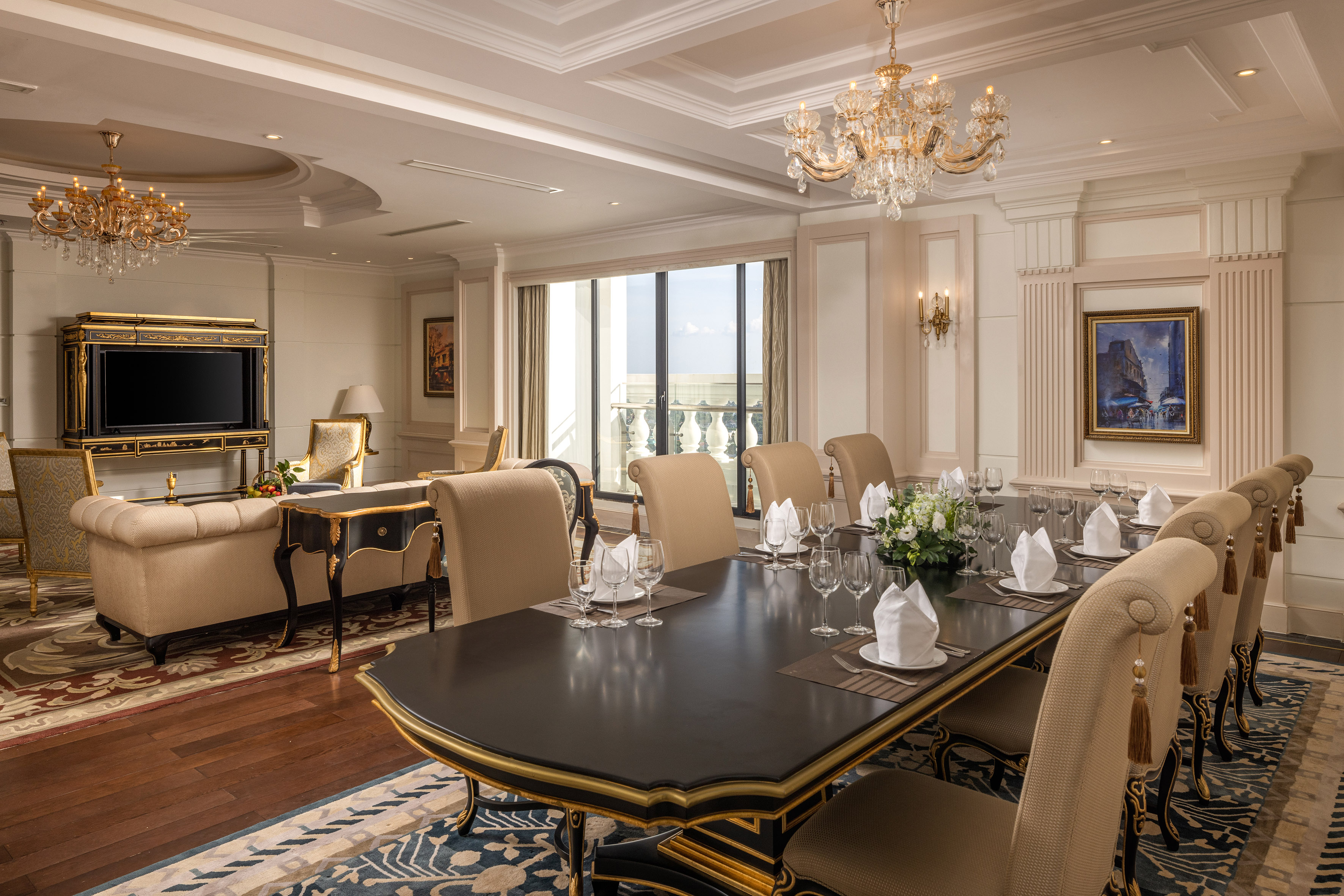 Luxury private dining room with chandeliers and adjacent living area.
