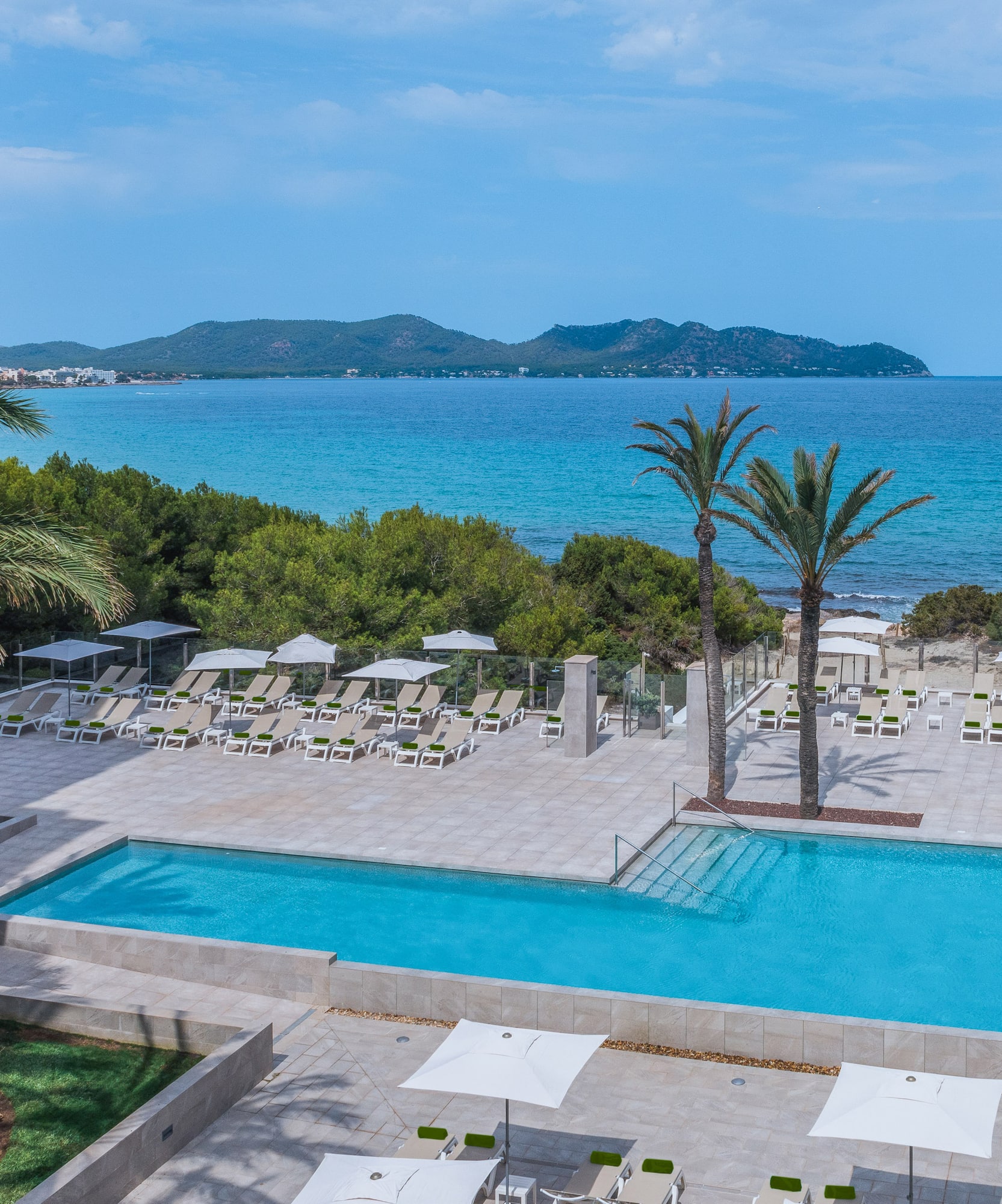 Resort pool terrace with sun loungers overlooking the blue sea and distant hills. - Meliá Cala Millor, Majorca